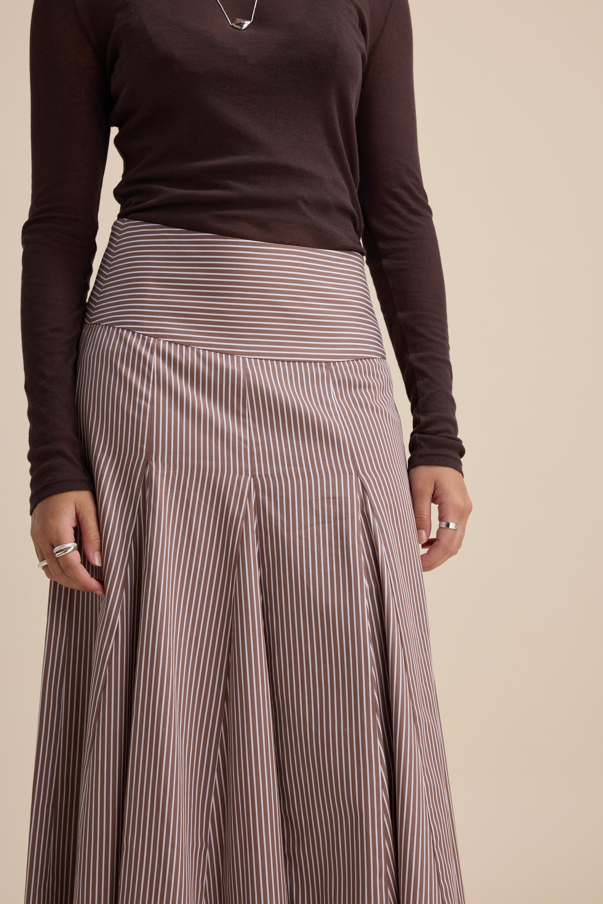 Person in a brown top and Max Marley Panel Seam Skirt, hands resting by their sides.