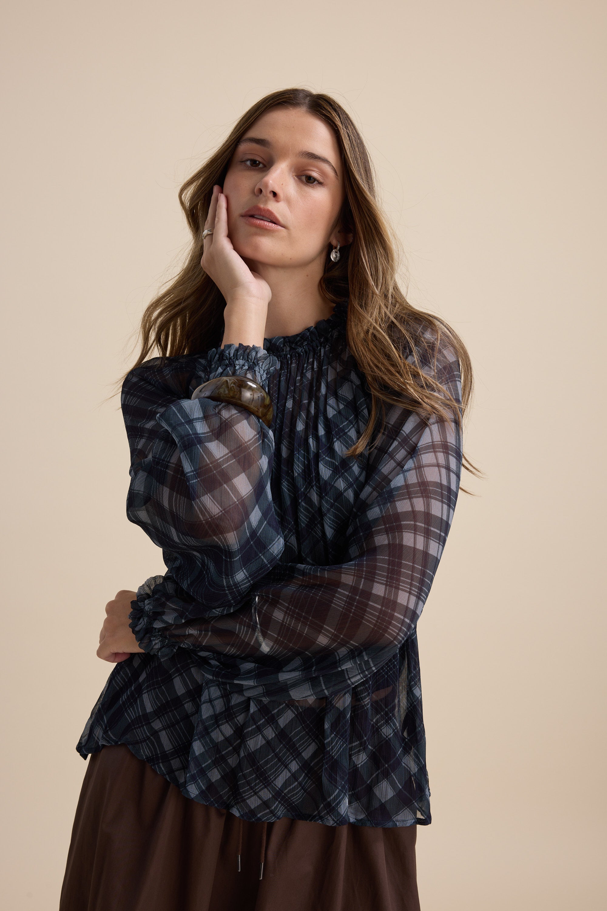 A woman models Max’s Quinn Gather Detail Blouse in sheer navy check with puff sleeves.