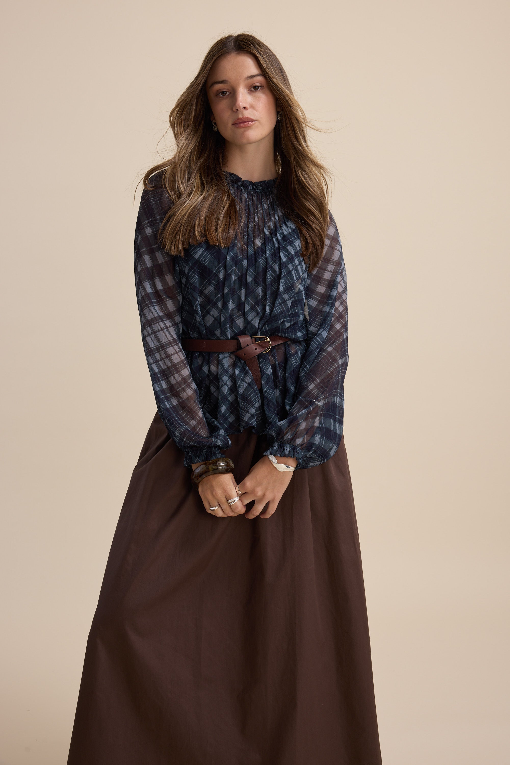 Woman in Max Quinn Gather Detail Blouse and brown skirt poses against a beige background.