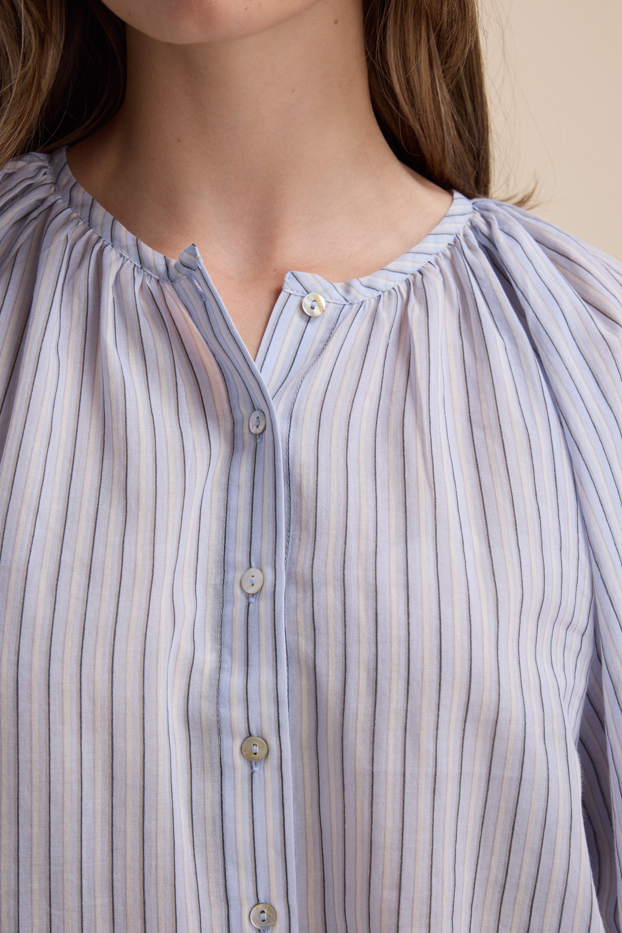 A person wearing Max's Vivian Button Front Blouse in light blue pinstriped organic cotton.