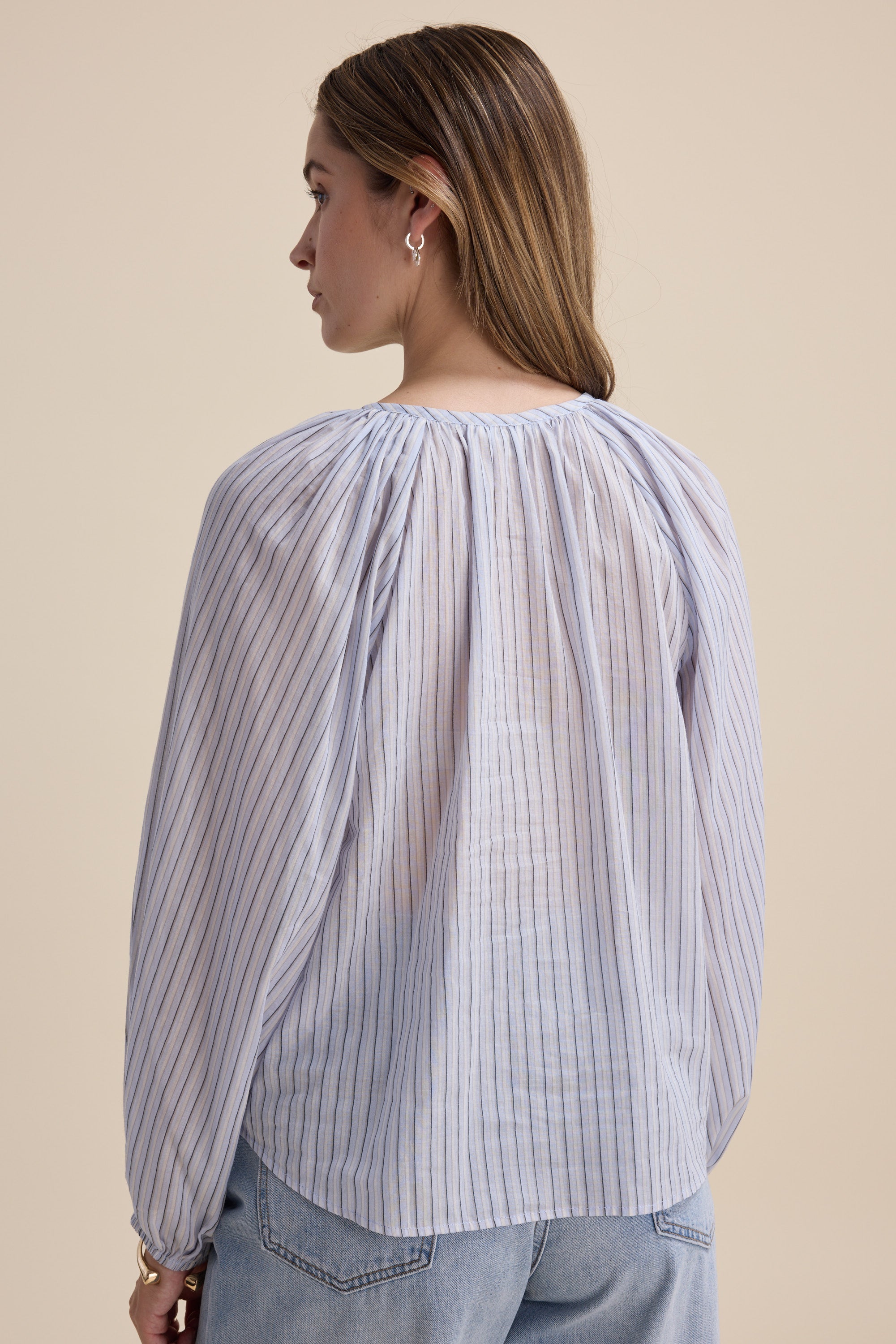 Woman in a Max Vivian Button Front Blouse and jeans, shown from the back.