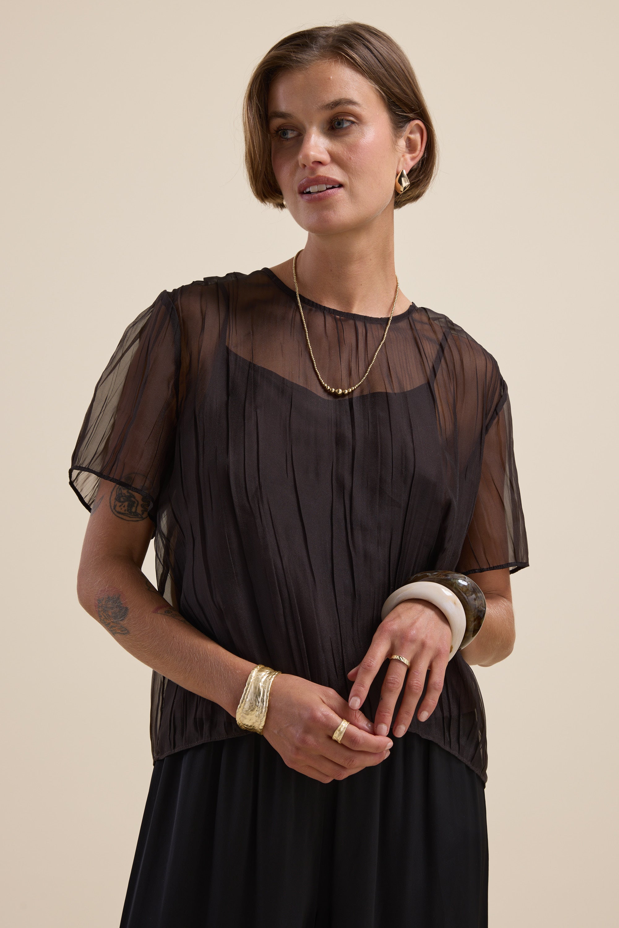 Max Cass Sheer Top styled with gold jewelry, short hair, and a cropped silhouette on beige.