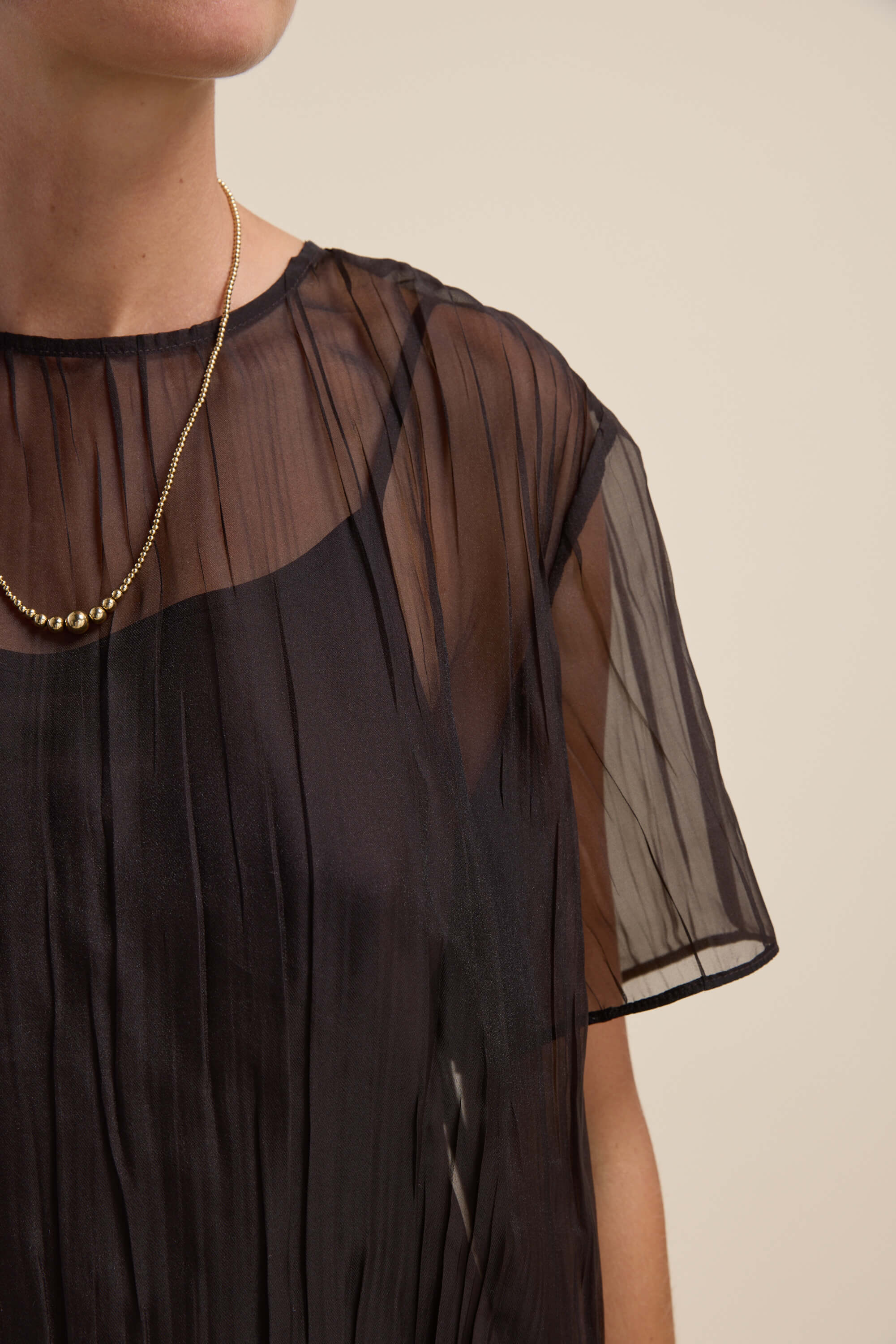 Model in Max’s Cass Sheer Top with detachable cami and a gold bead necklace.