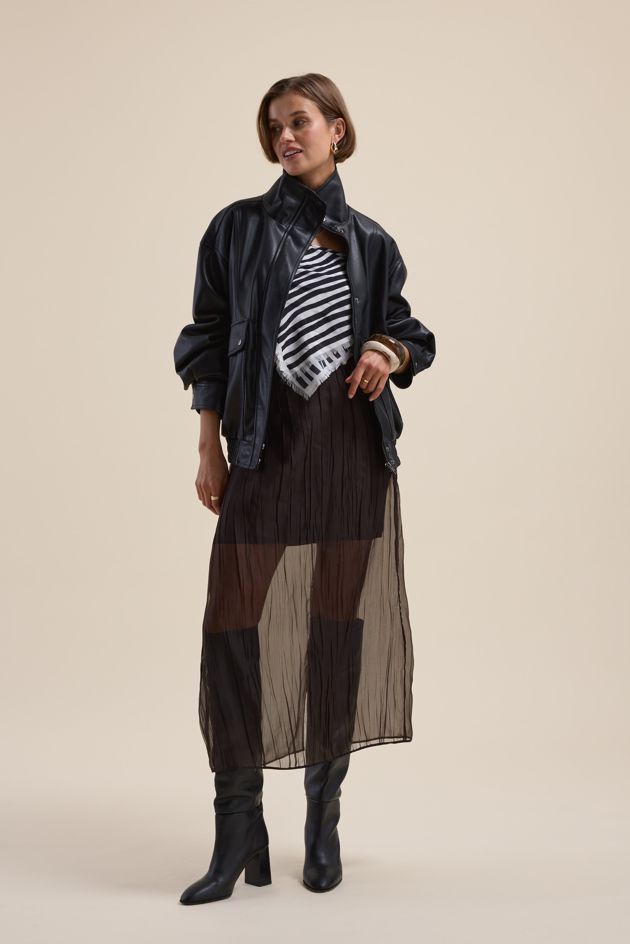 Woman in a black jacket, striped top, Max Ari Sheer Midi Skirt, and black boots.