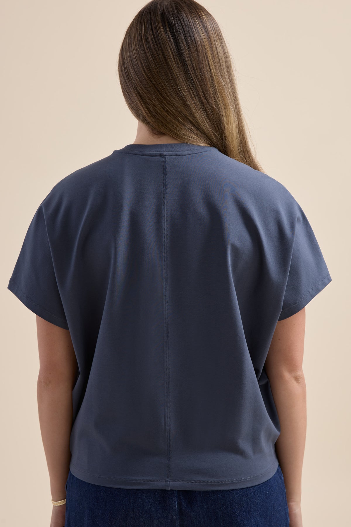Person with long brown hair in an Elementary Slouchy Short Sleeve Tee, shown from the back.