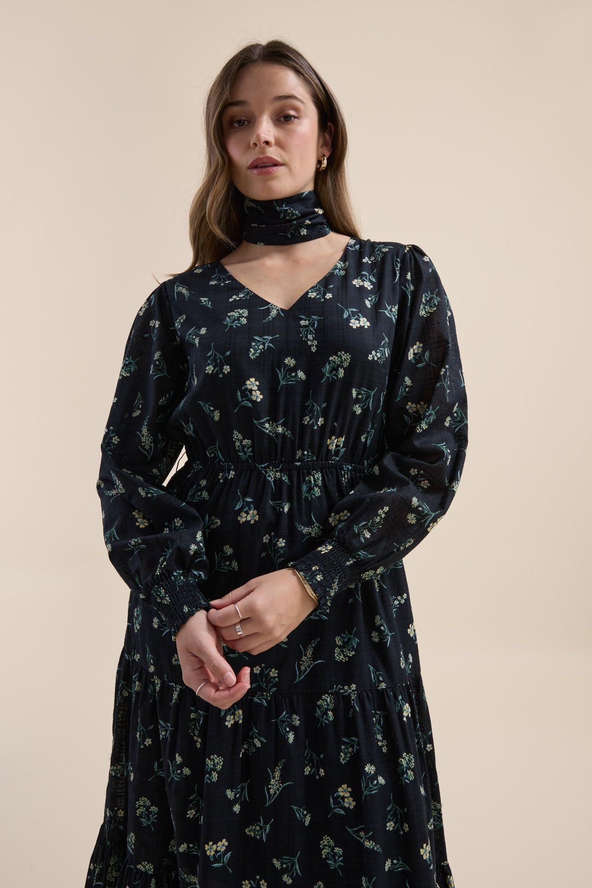 Woman in Elementary Tiered Dress with Daisy Sprig Print, scarf, posed against beige background.