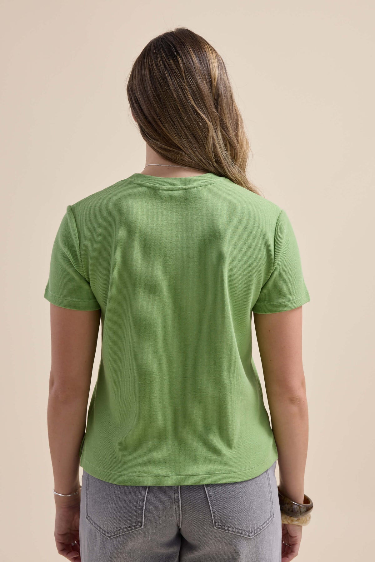 Person with long hair in Elementary Ribbed Boxy Tee, back view against plain background.