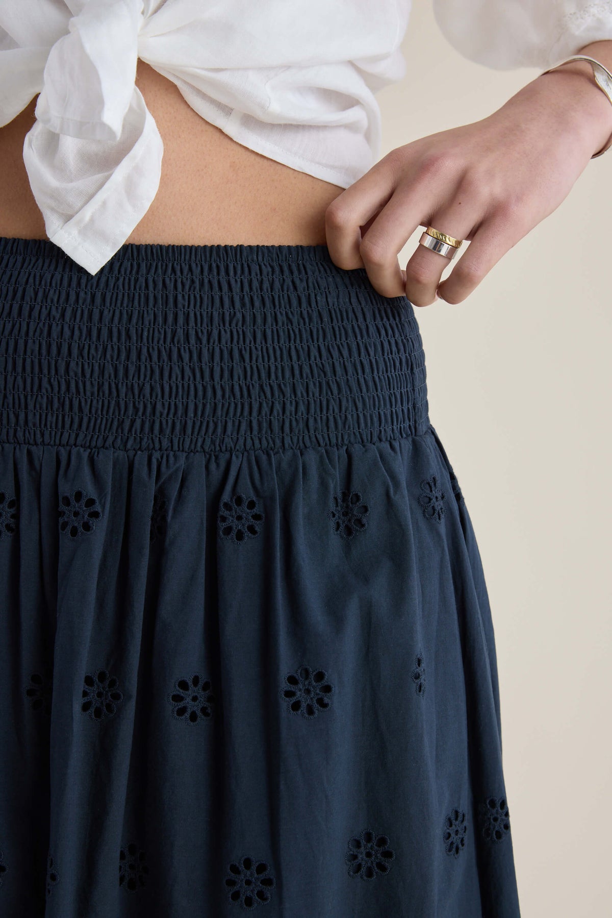 Hand on an Elementary Broderie Detail Skirt with cutouts, paired with a white tied blouse.