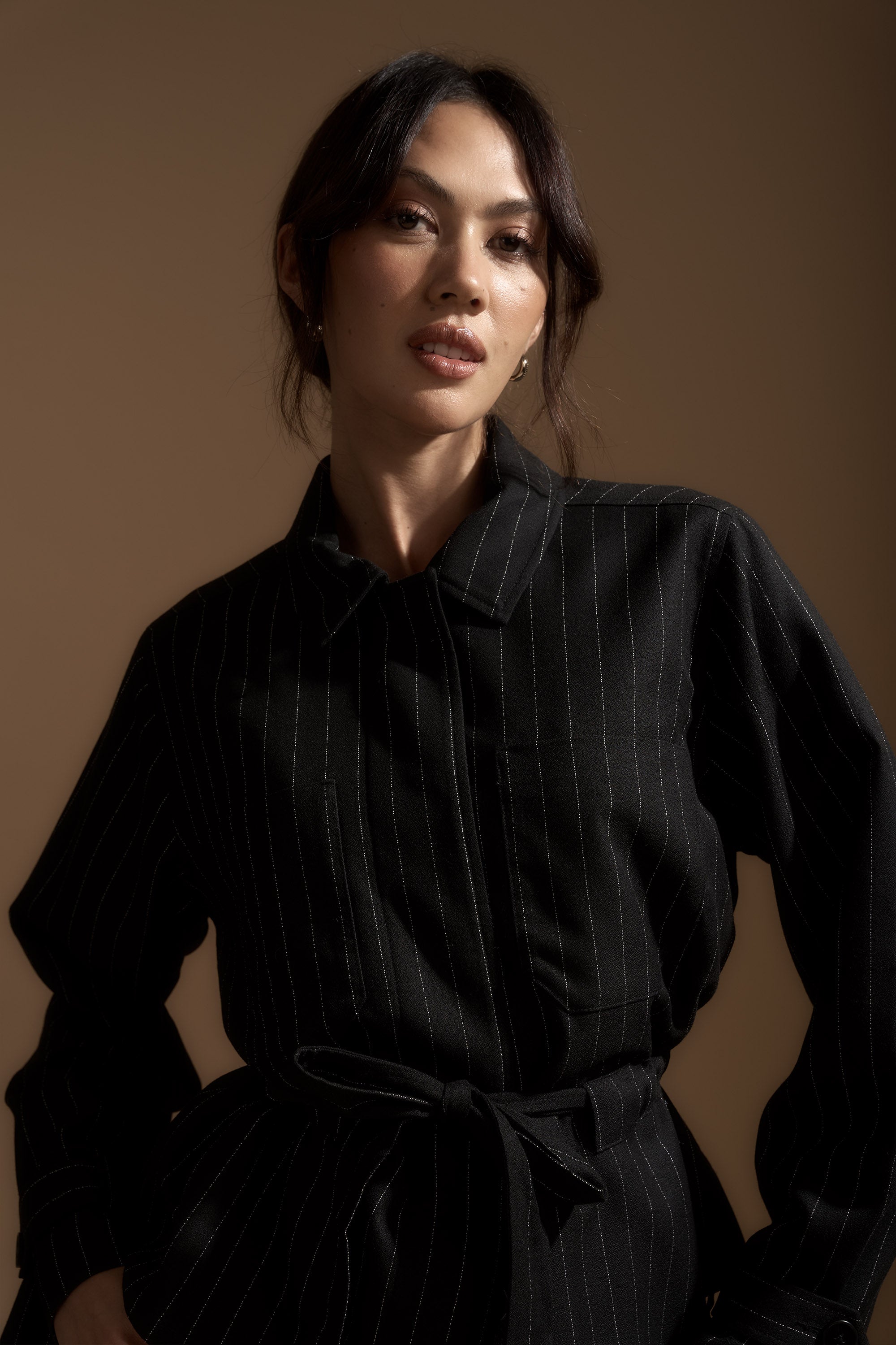 Woman wears the Juliette Belt Detail Jacket by Max, standing against a brown background.