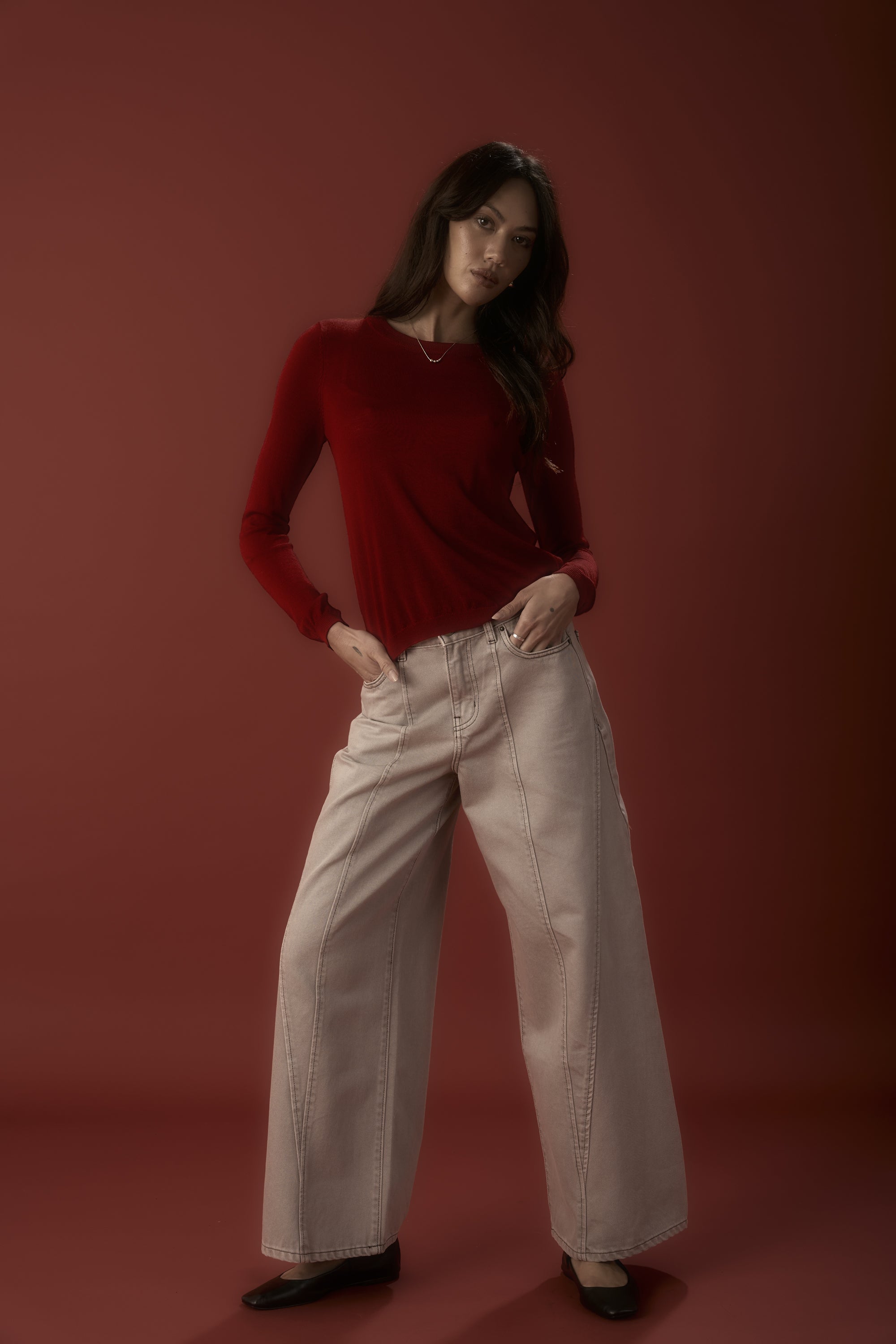 Woman in Lisbon Panel Detail Jeans by Max poses against a vibrant red background.