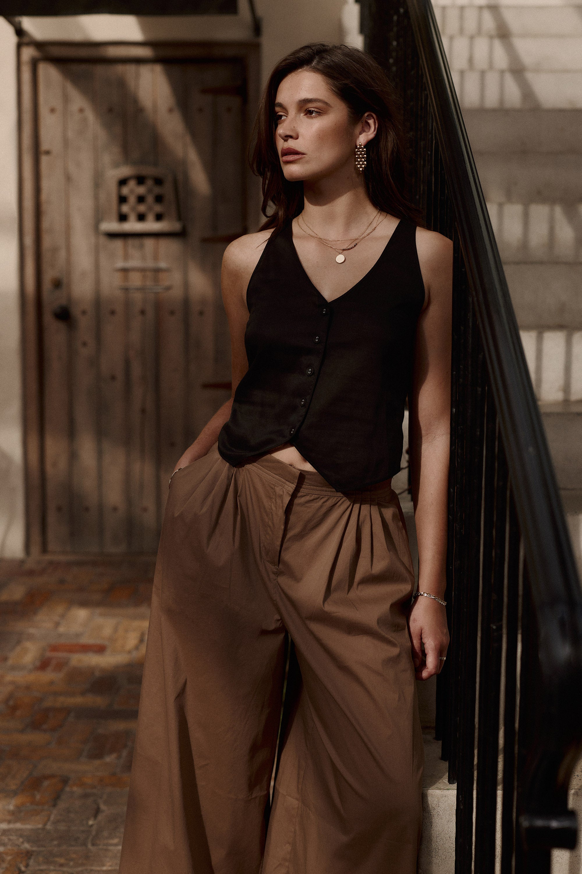 Woman in the Tia Sheer Vest Top by Max and brown wide-leg pants, a spring essential.