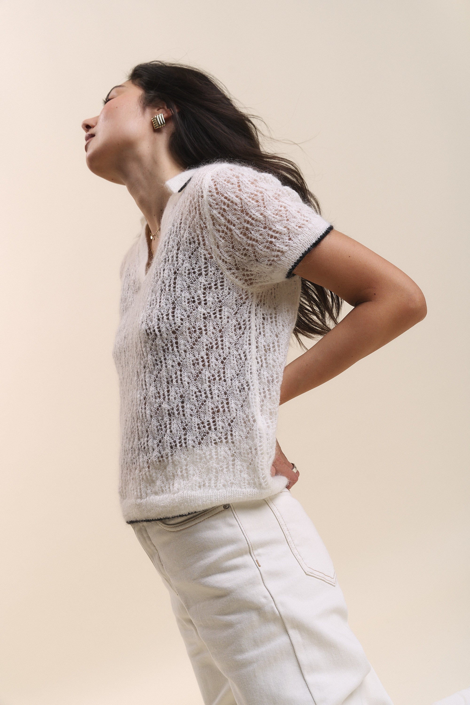 Woman wears Max Taylor Short Sleeve Knit and white pants, posing with hands on her back.