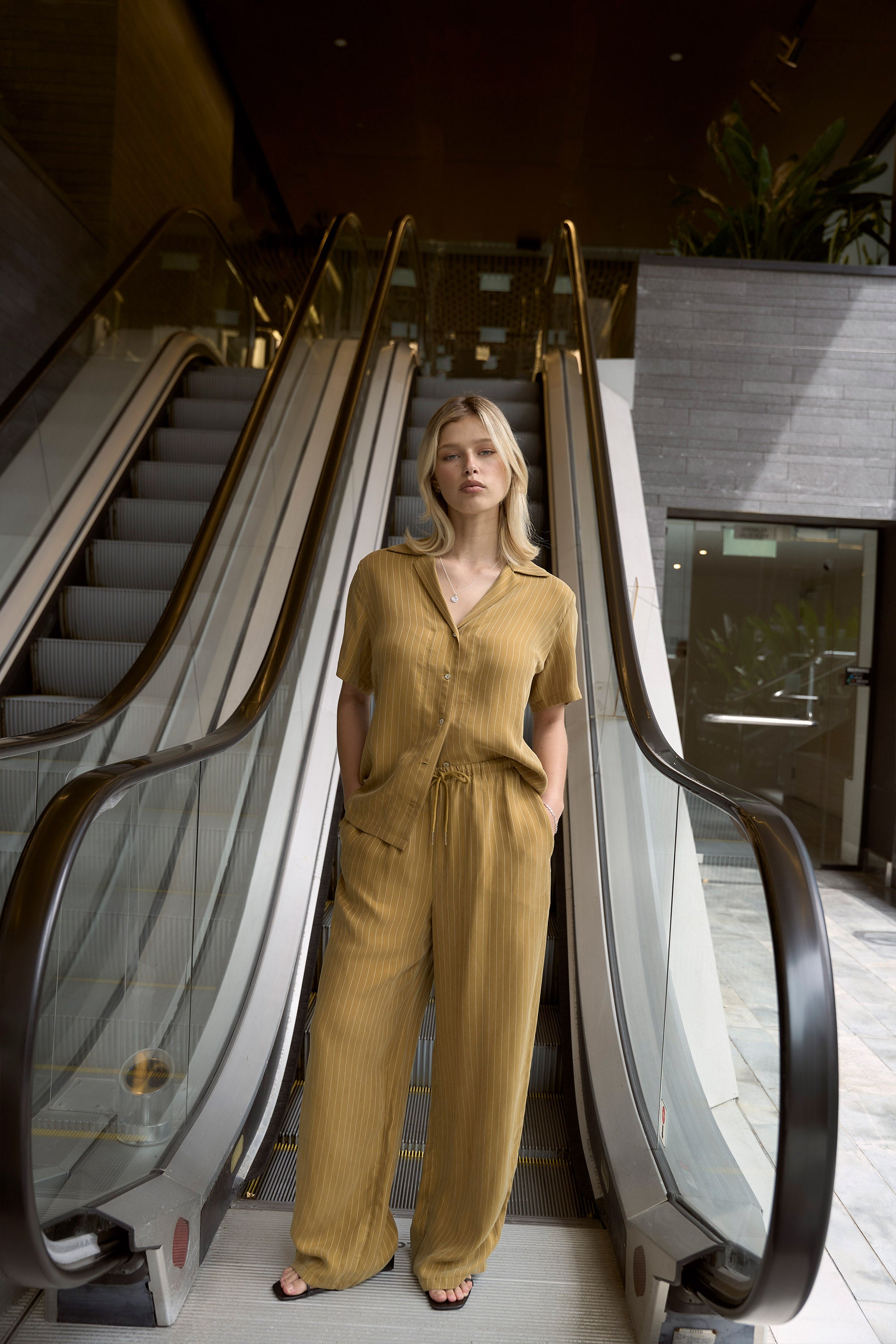 Woman in the Amy Short Sleeve Shirt by Max stands between two escalators.
