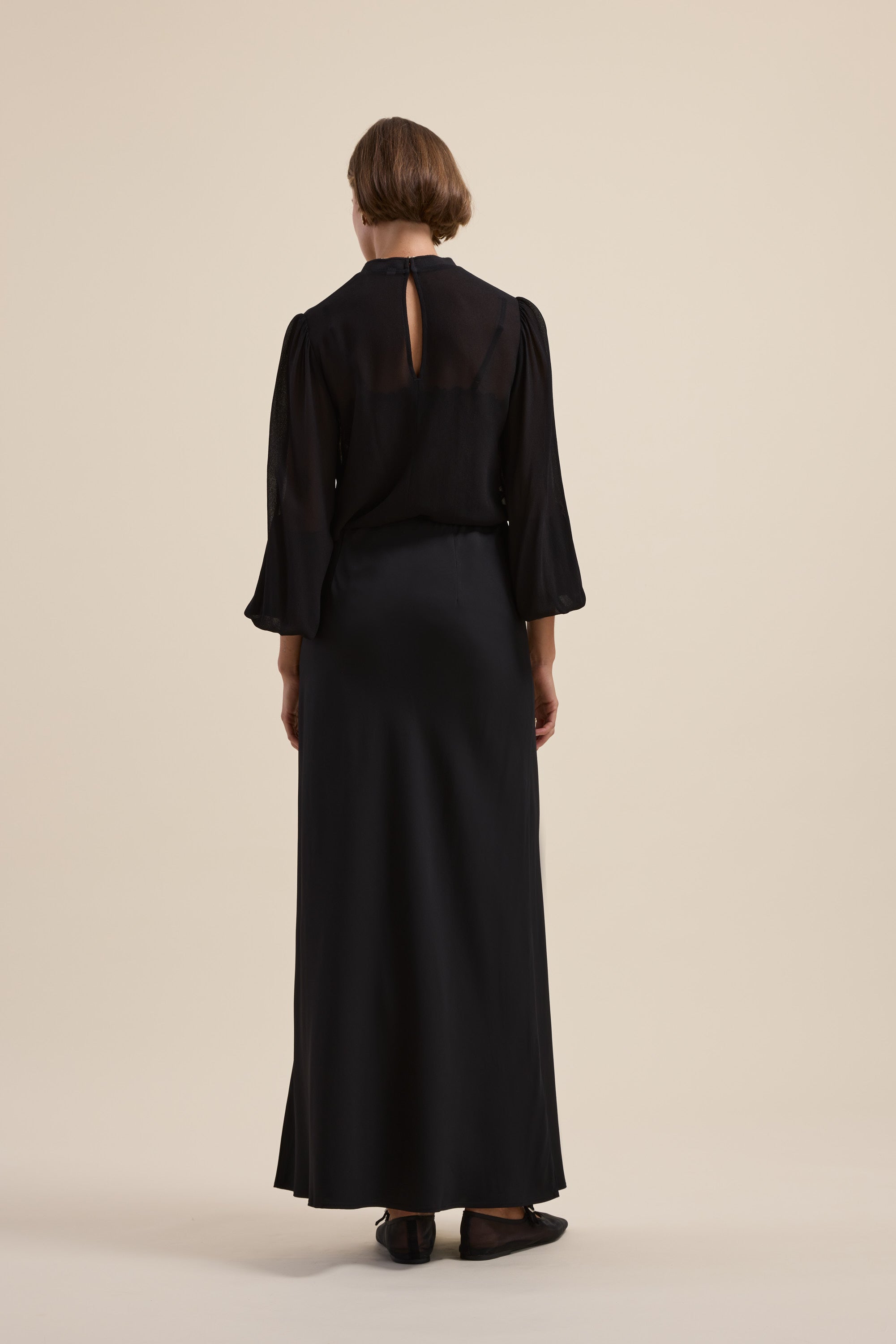 Person in a Maxi Slip Skirt by Max, long-sleeved black dress, back to the camera.