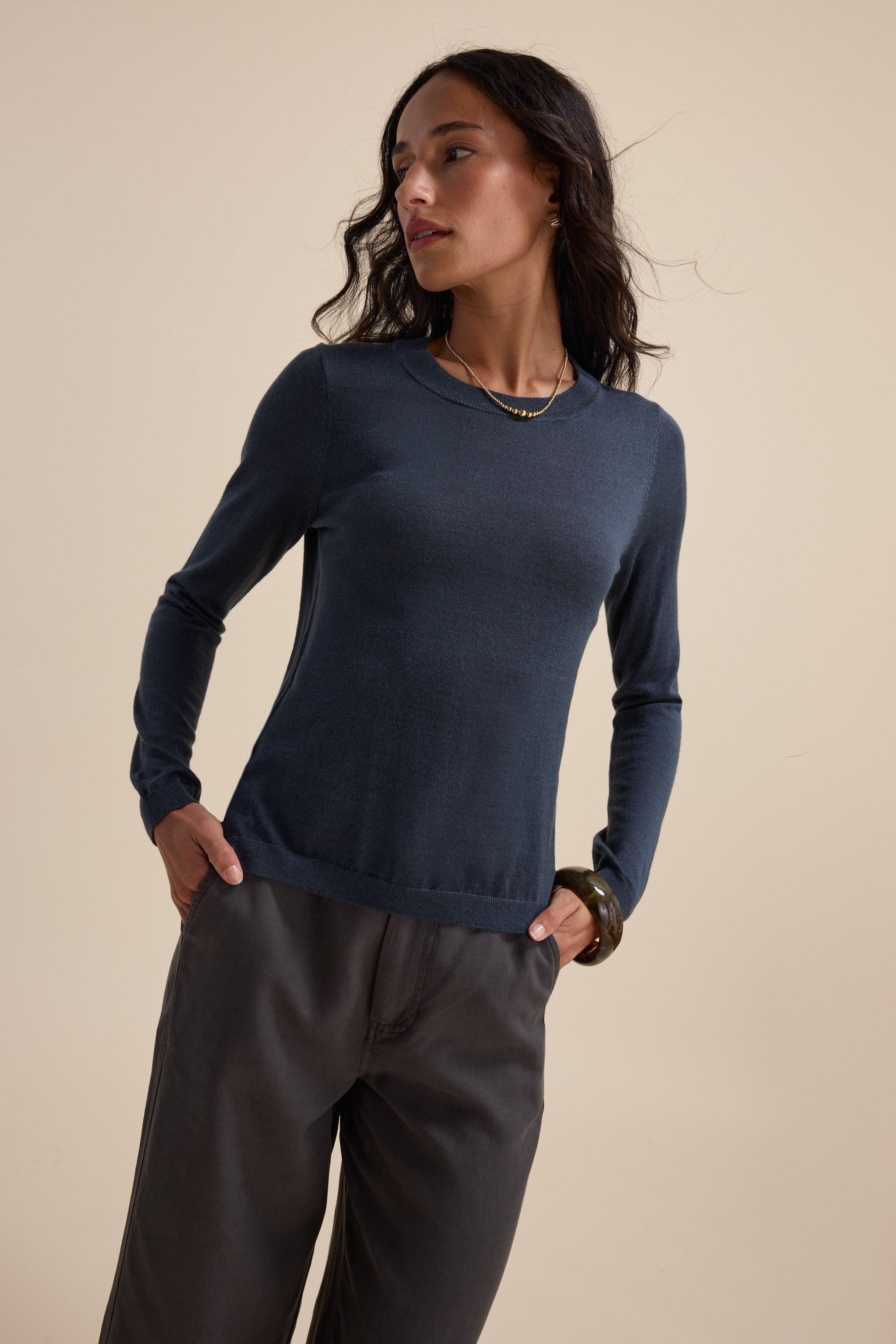 Woman in the Max Merino Silk Layering Top and loose pants, looking to the side, hands in pockets.