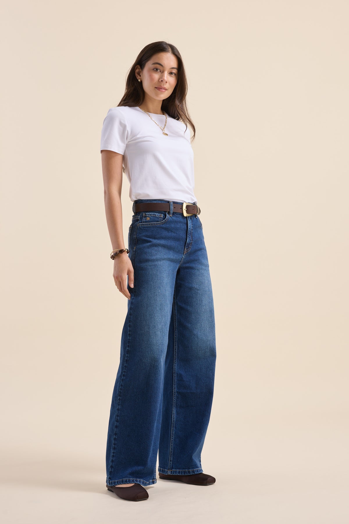 Woman in a white tee and Max Nevada Wide jeans stands against a beige background.