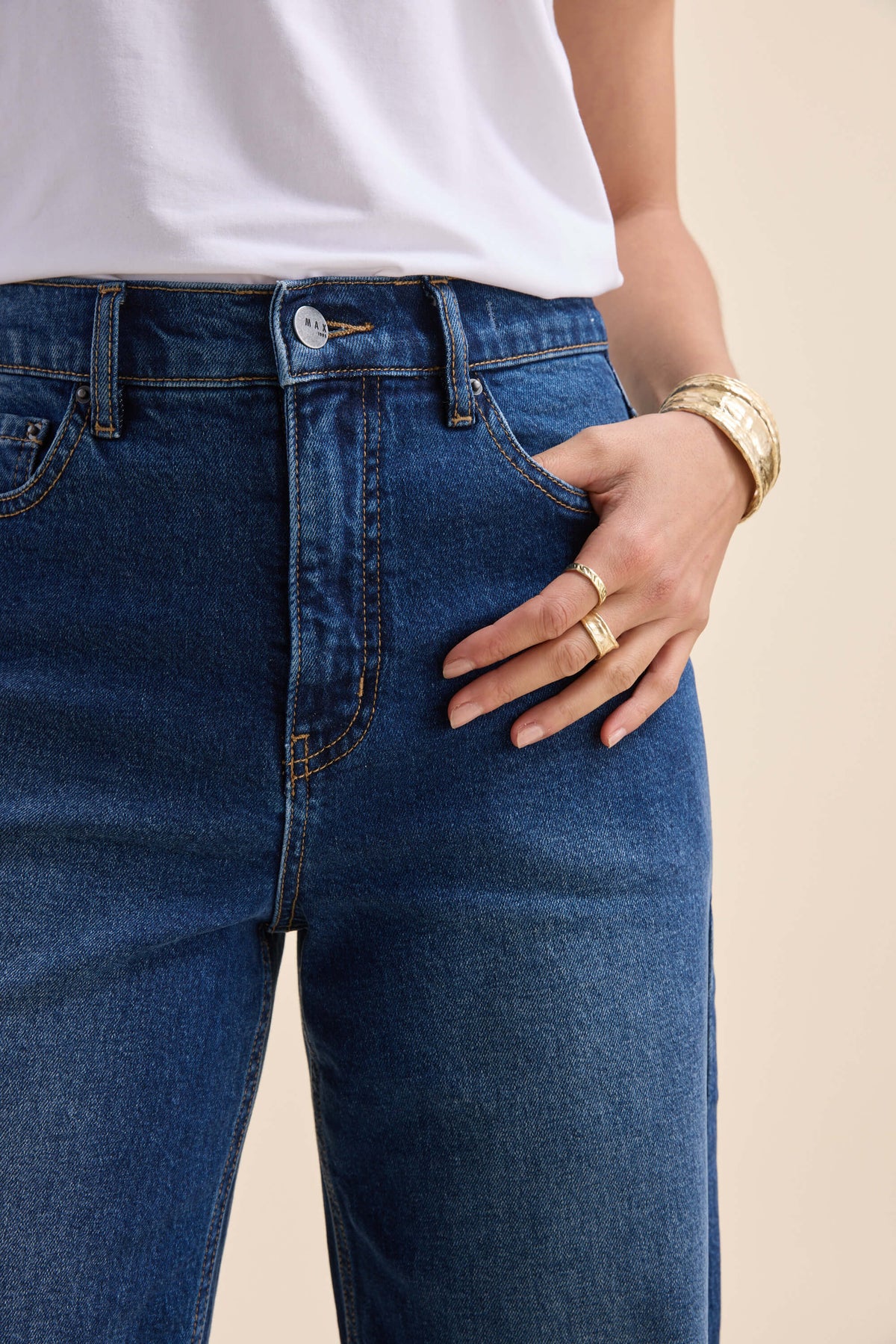 Person in Max Nevada Wide jeans, white shirt, gold rings, bracelets, hand in pocket.