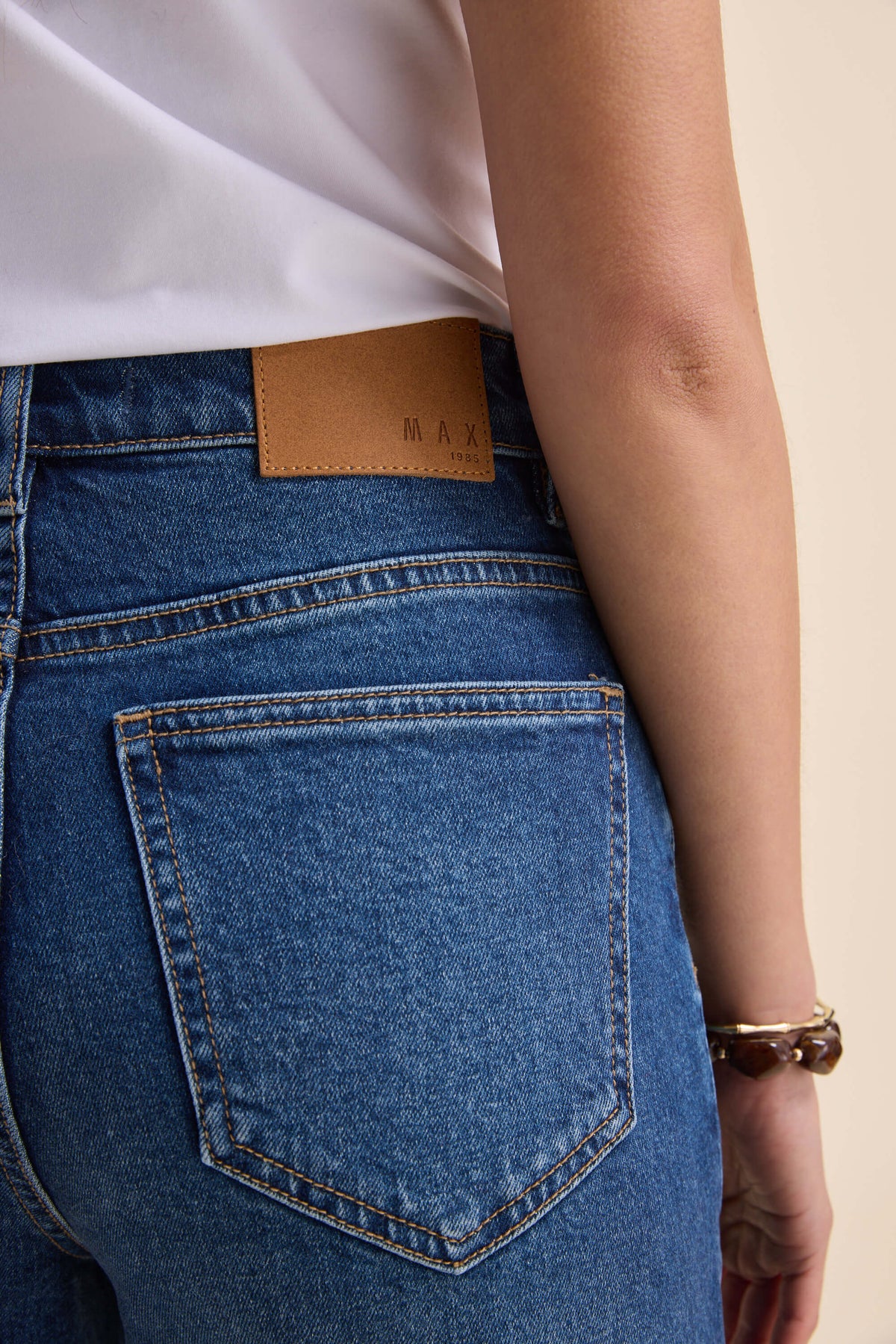 Person wearing Max Nevada Wide jeans and a white shirt, showing back pocket and brown label.