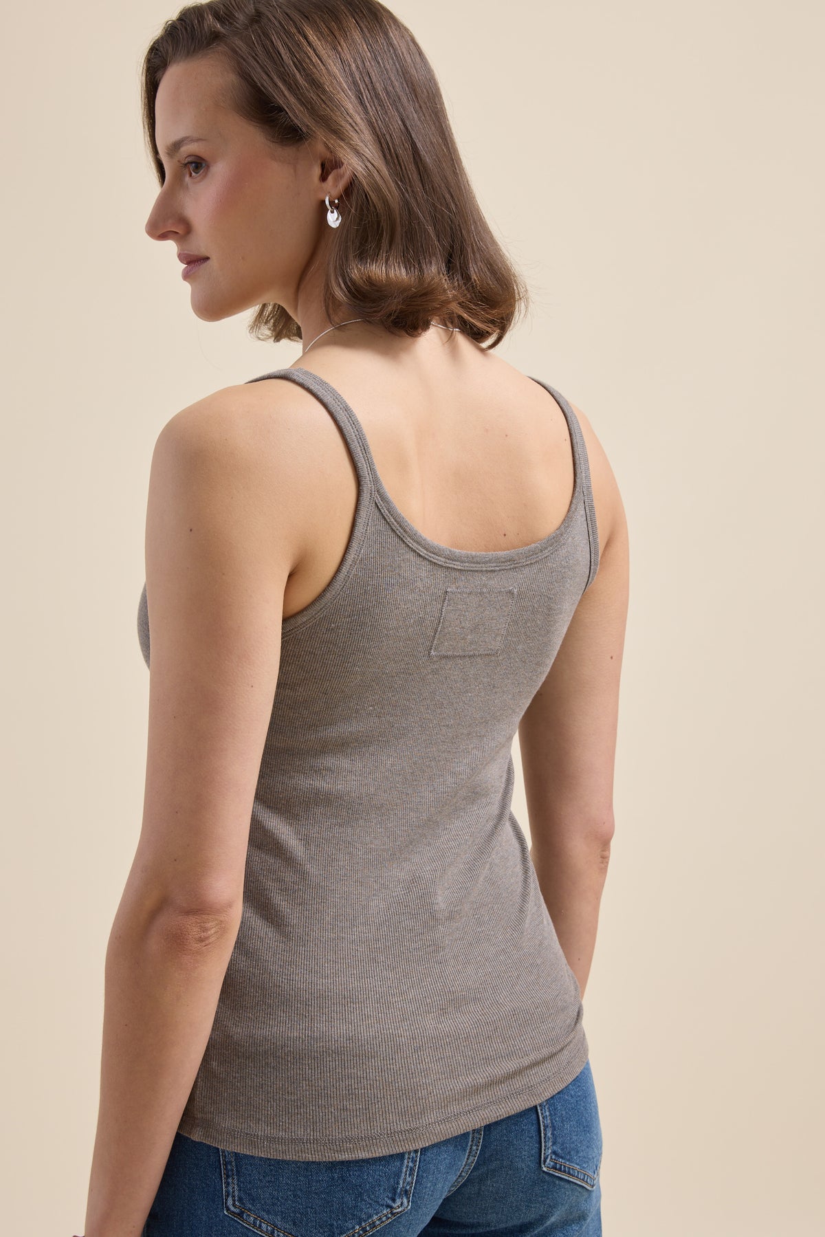 Woman in Elementary Basics Rib Cami and jeans, facing away, with short brown hair.