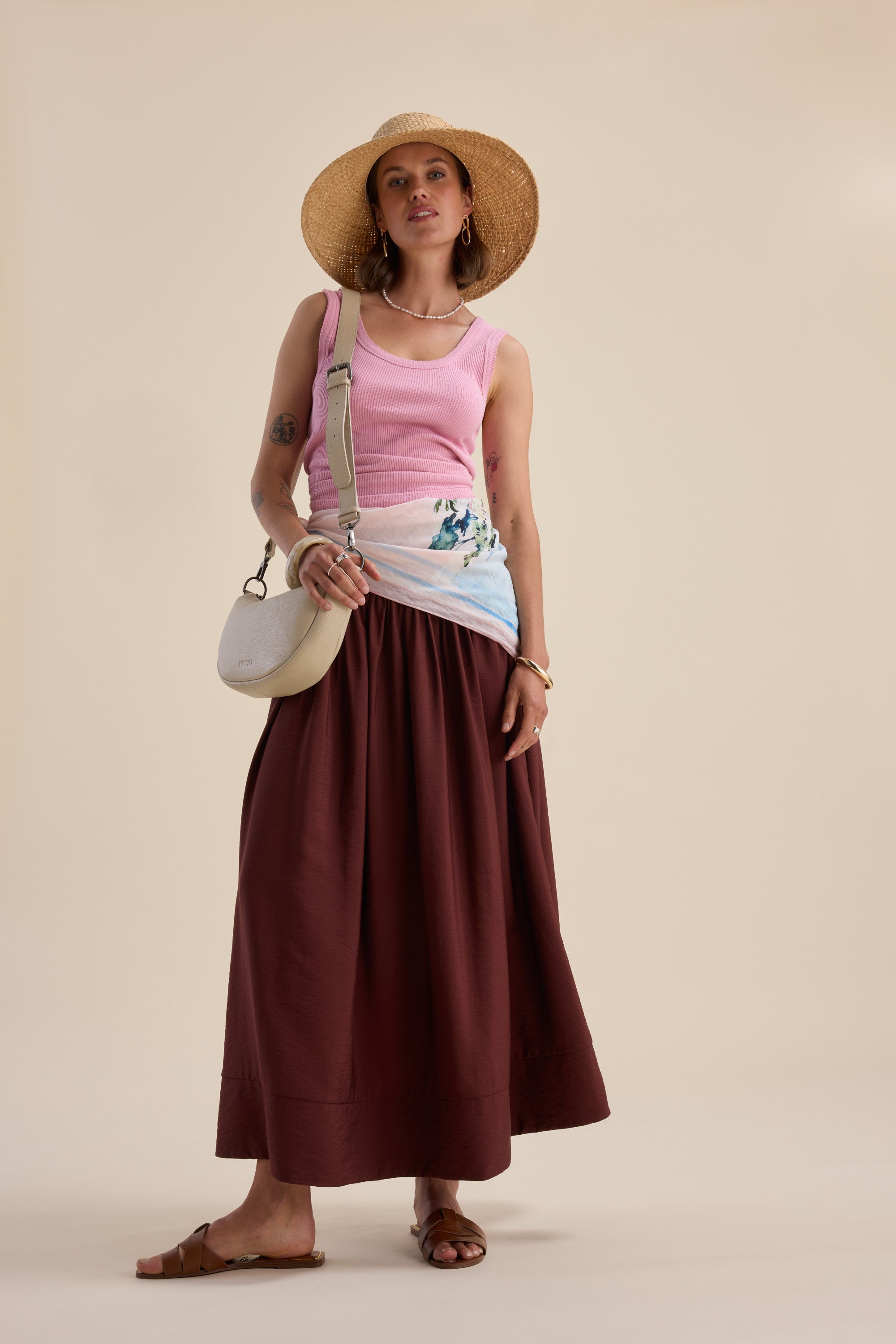 Woman in a straw hat, pink tank, Max Carrie Tiered Skirt, sandals, and crossbody bag.
