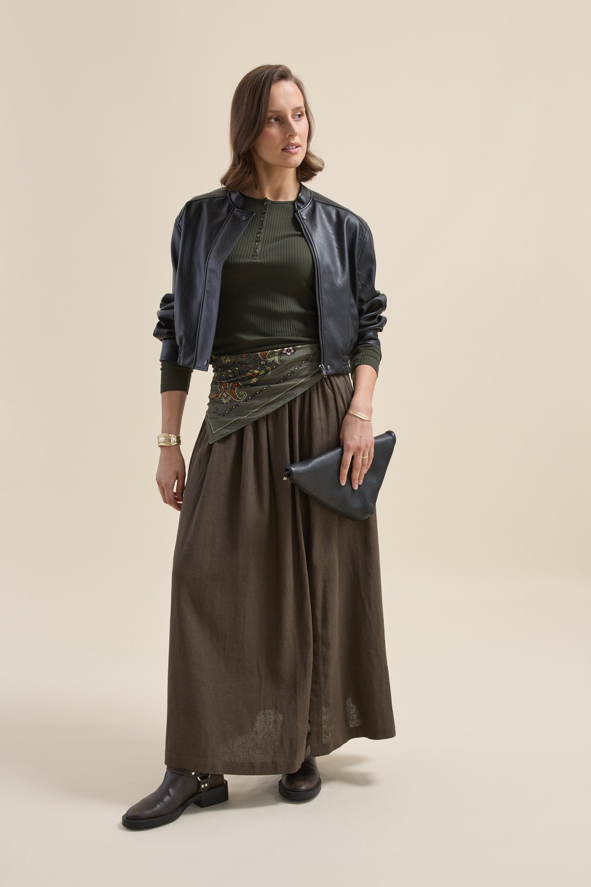 Person in a black jacket, Elementary Ribbed Henley green top, brown skirt, black clutch.