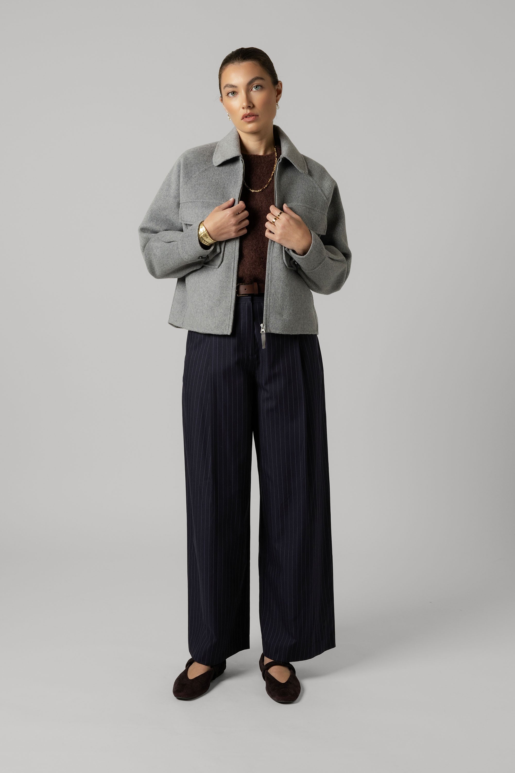 Woman in Max's Zip Front Wool Blend Cropped Coat, brown sweater, navy pants, and flats.