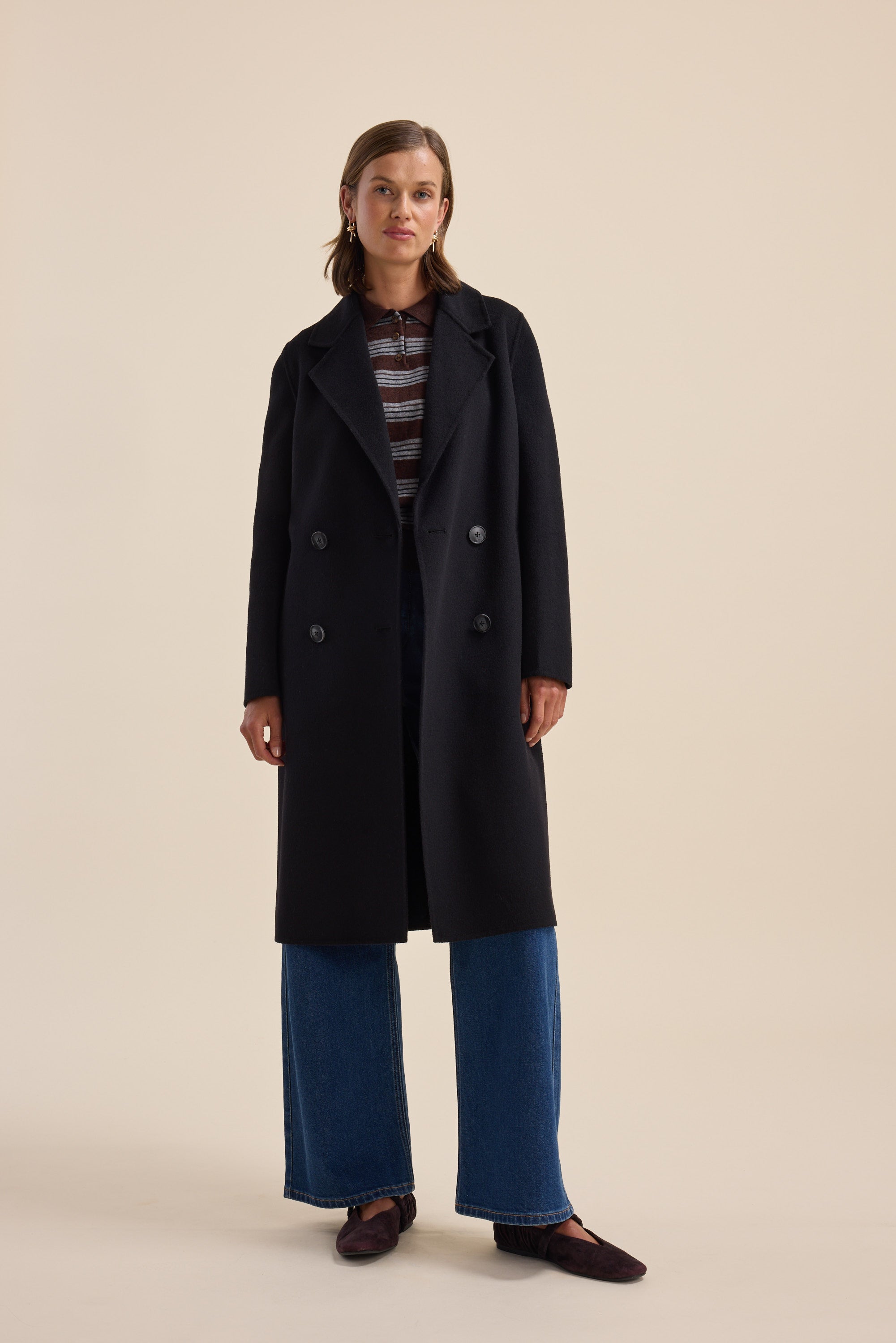 Woman in The Belted Wool Coat by Max, striped shirt, wide-leg jeans, and loafers, standing.