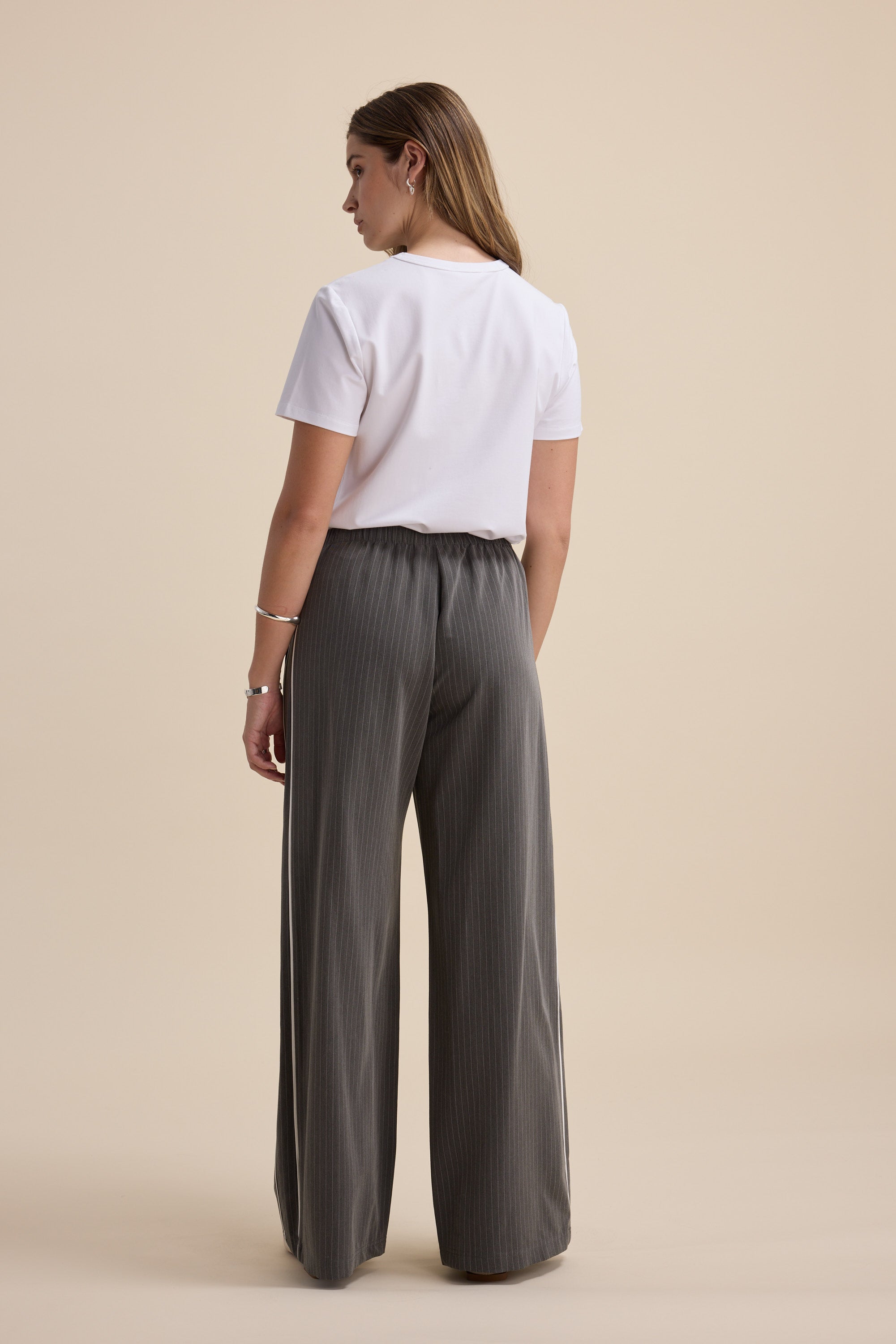 Woman in Max's The Elevated Jogger and a white tee, standing against a beige background.