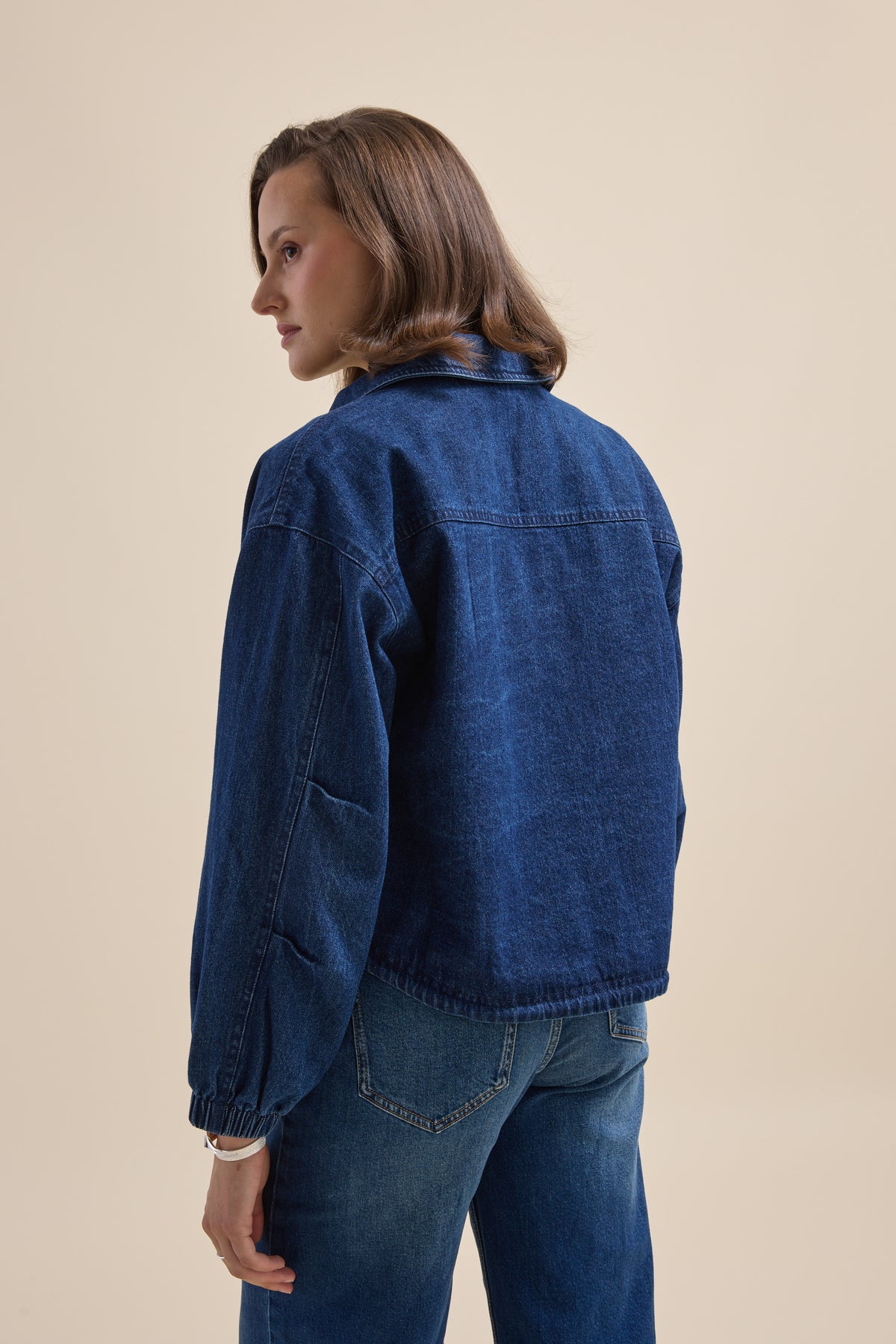 Back view: person in Elementary Relaxed Jacket and jeans, relaxed stance.