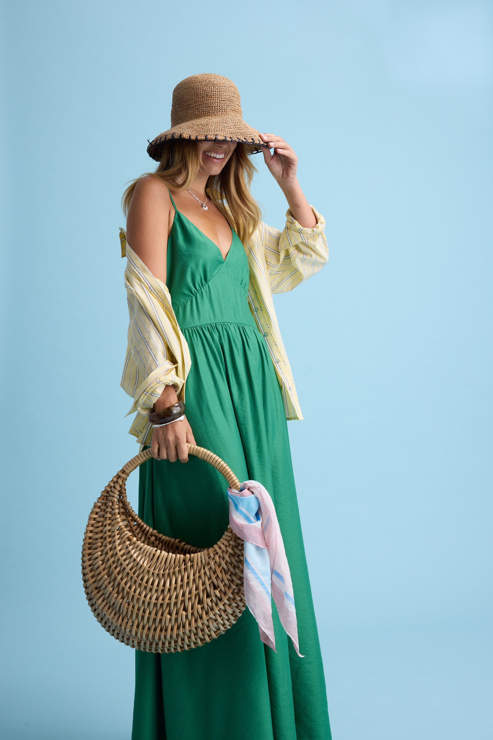 Woman in green dress, straw hat, with Max Portia Silk Blend Square Scarf and woven bag, blue bg.