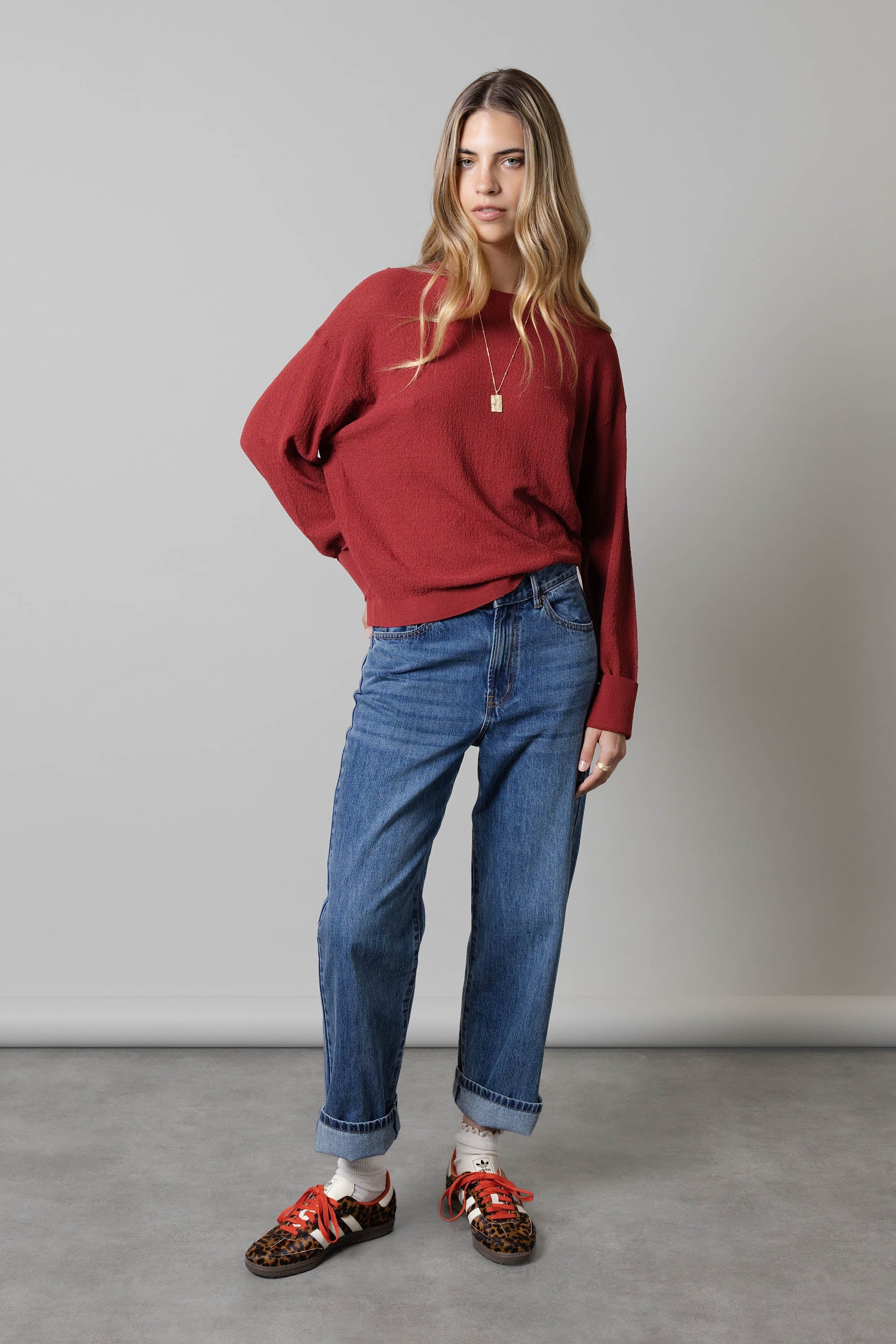 Woman in a red sweater, Max Borrowed From The Boys Jeans, and leopard print shoes on gray.