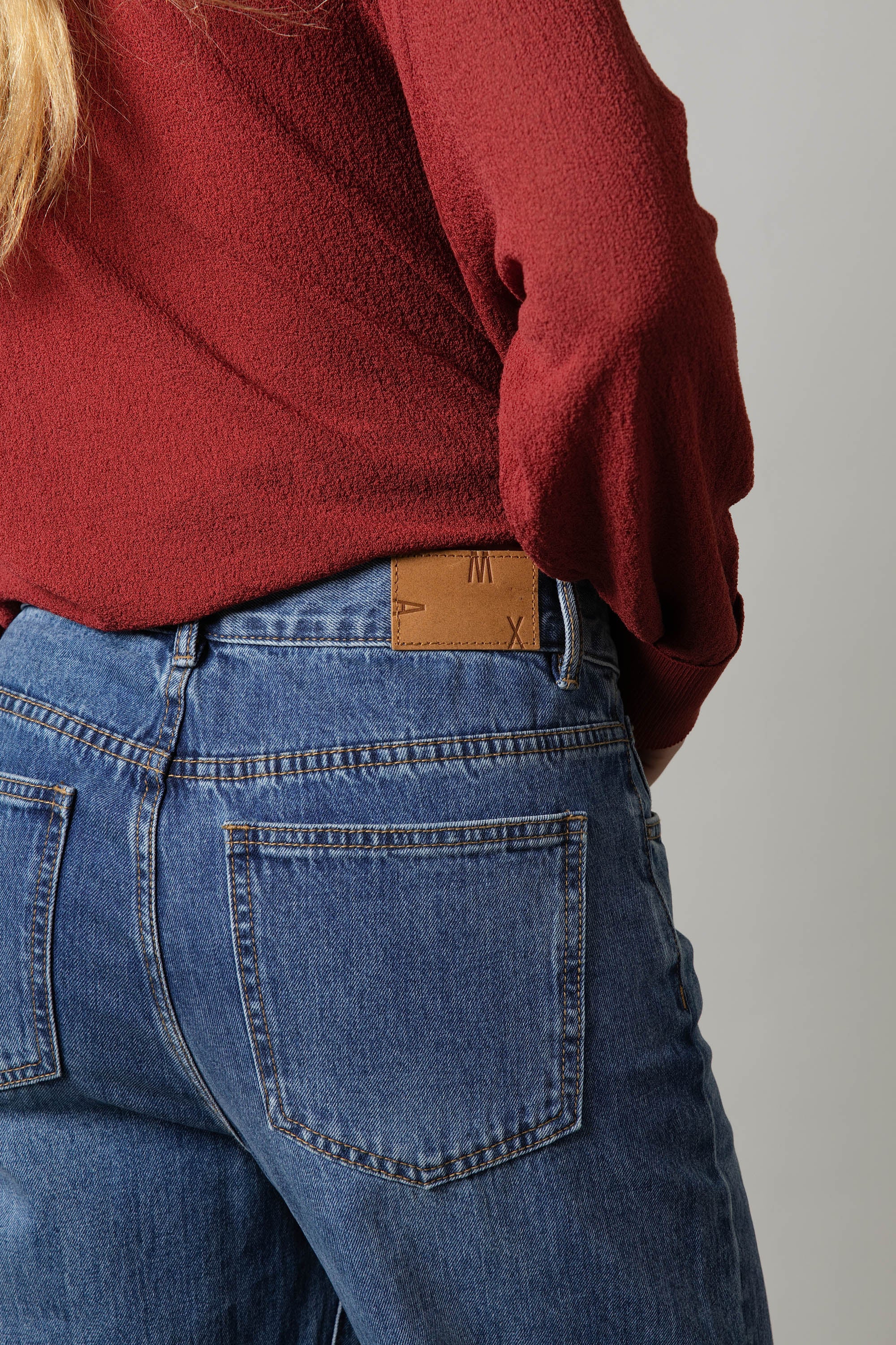 Person wearing Max Borrowed From The Boys Jeans and a red textured top, shown from the back.