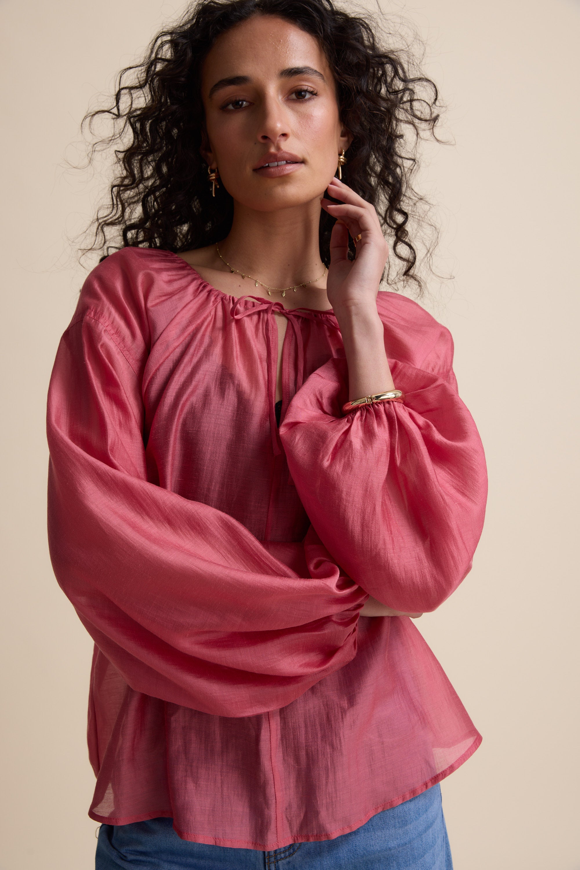 Woman in Max's Abigail Tie Neck Blouse with puff sleeves, against a beige background.