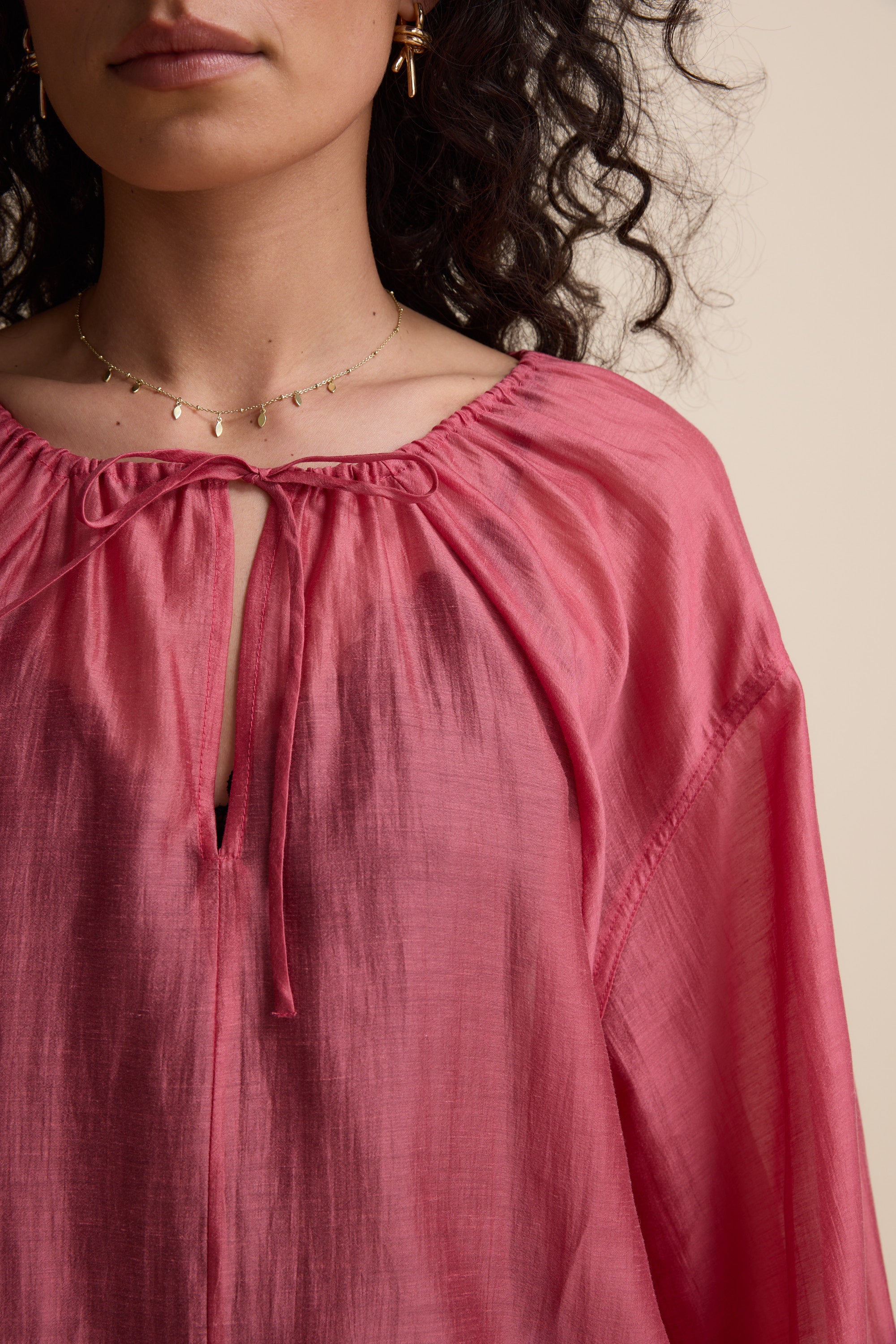 Woman in Max's Abigail Tie Neck Blouse, gold necklace, and curly hair.
