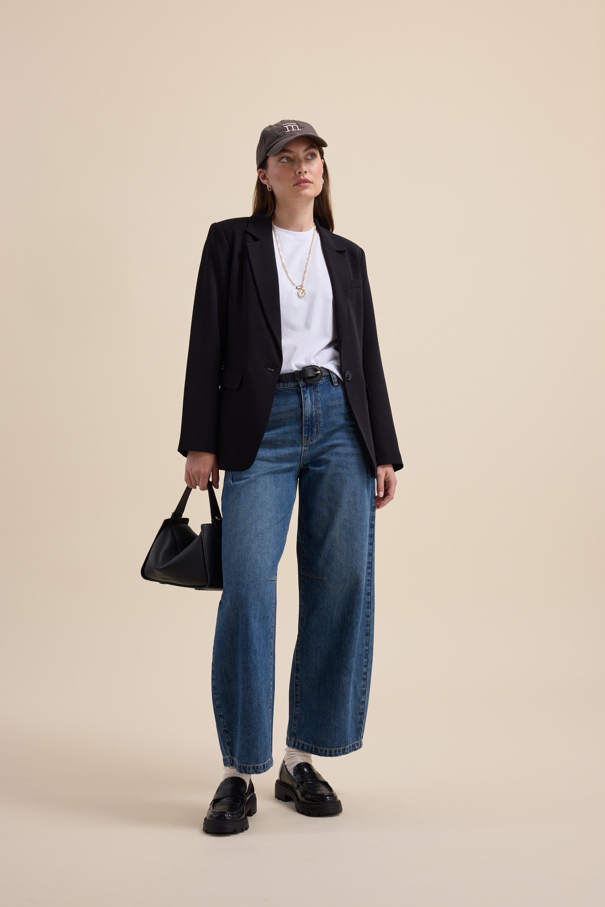 Woman in Max’s The All Occasion Blazer, wide-leg jeans, white shirt, cap, and black handbag.