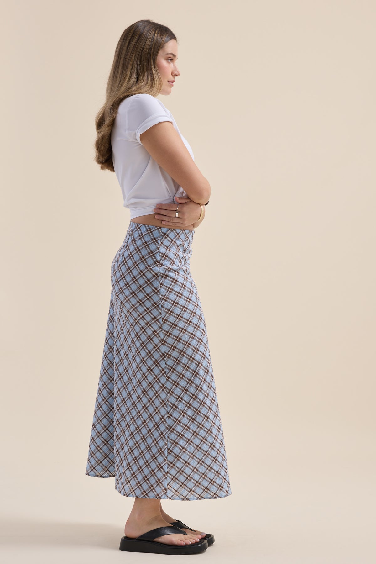 Woman in The Perfect Slip Skirt by Max, white shirt, arms crossed, standing in sandals.