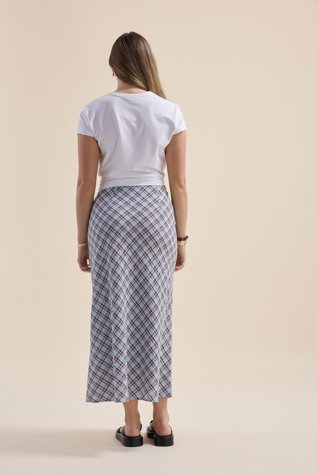 Woman in a white shirt, The Perfect Slip Skirt by Max, and sandals, facing away.