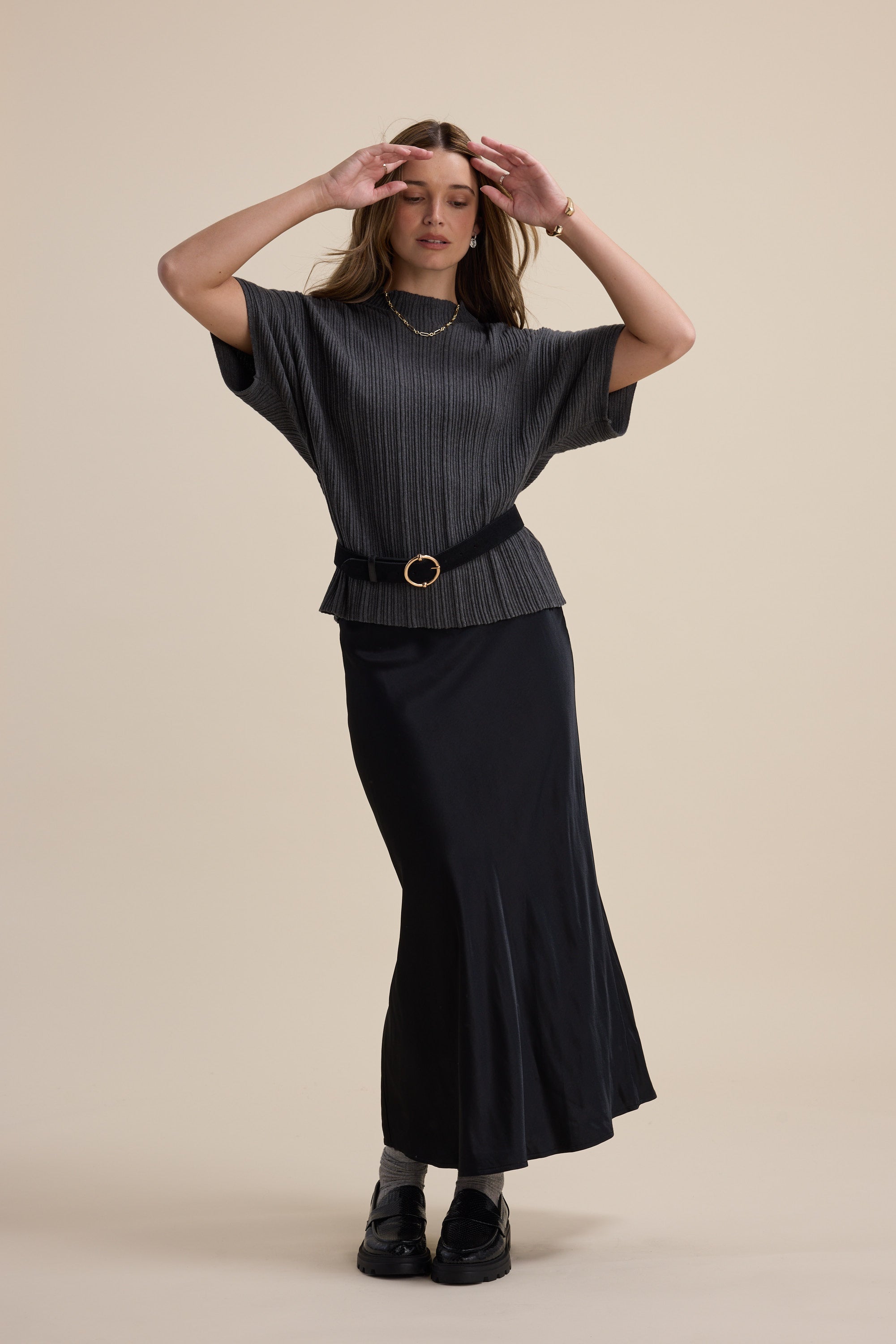 Woman in gray top and Max's The Perfect Slip Skirt posing against a beige background.