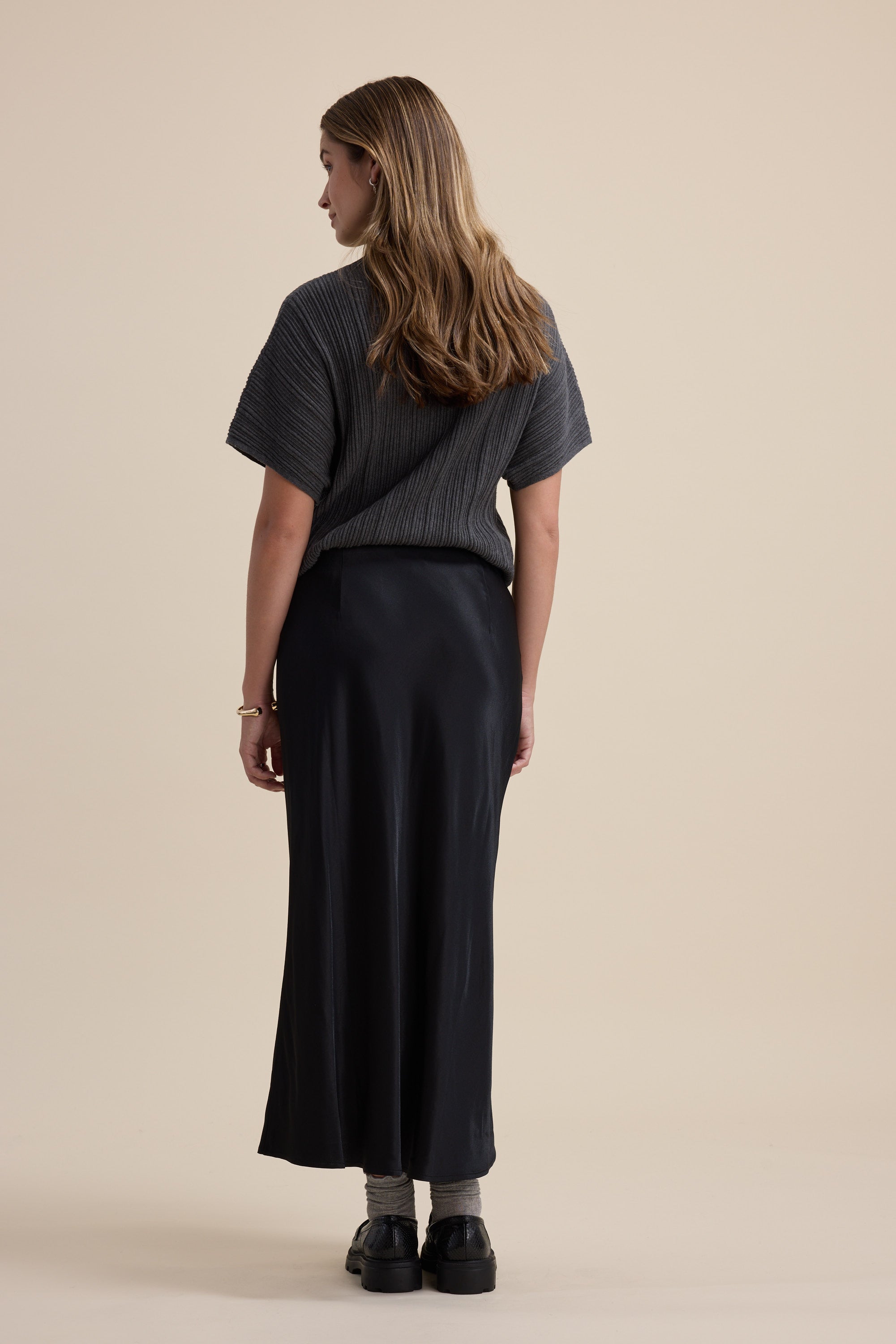 Woman stands with her back to camera, wearing Max's The Perfect Slip Skirt and a short-sleeve top.