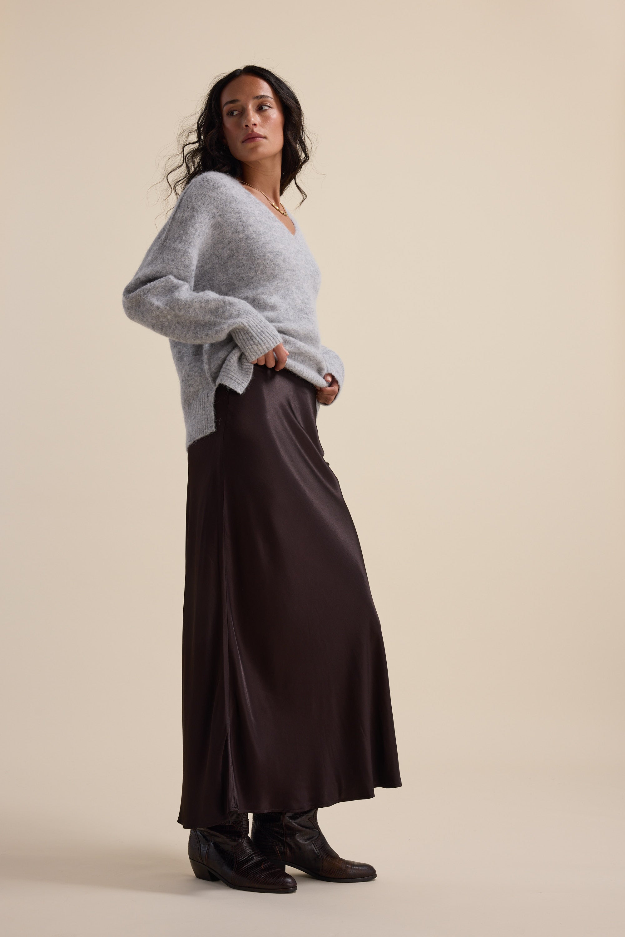 Woman in gray sweater and Max's The Perfect Slip Skirt stands against a beige background.