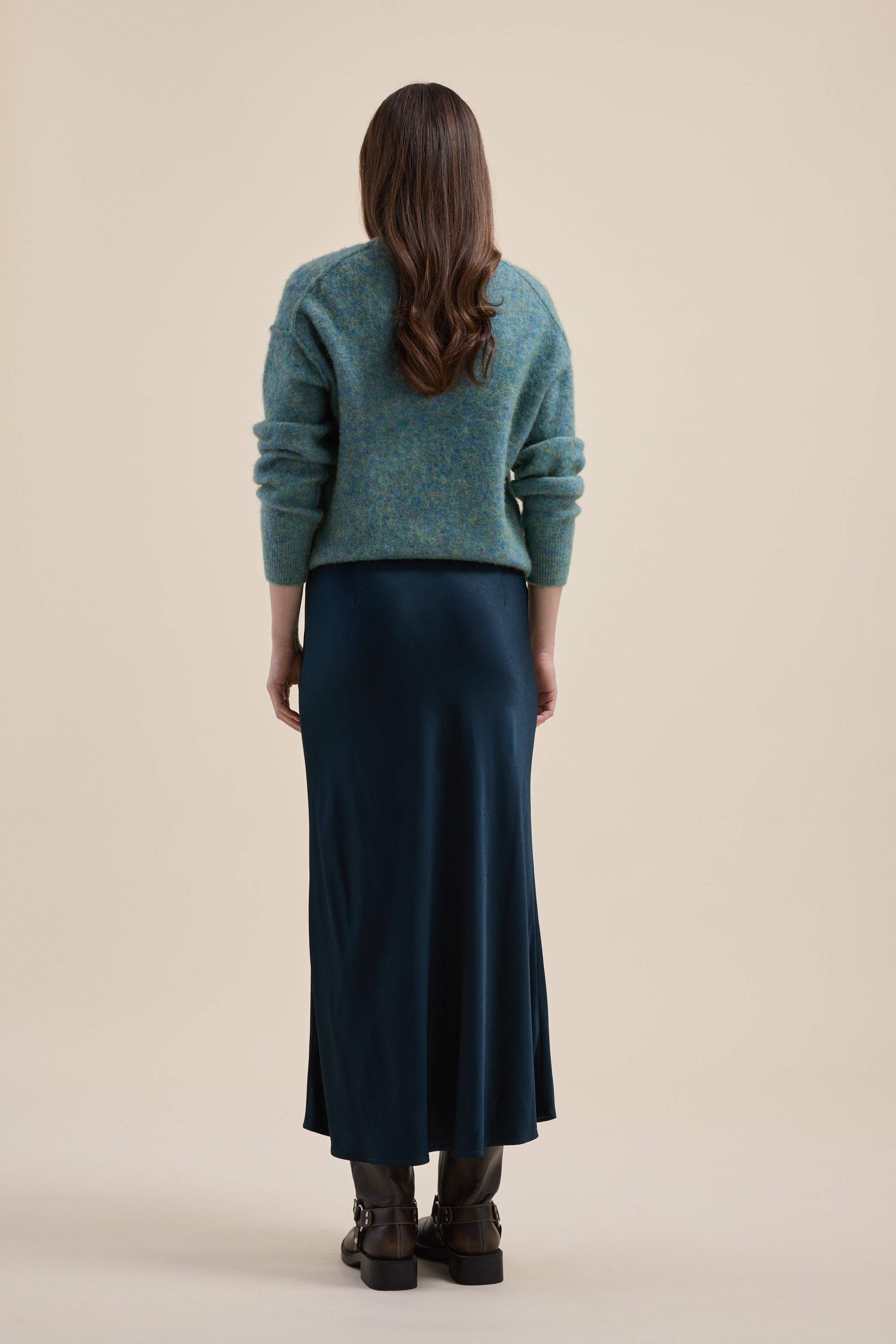Woman in a teal sweater and Max's The Perfect Slip Skirt, standing on a beige background.