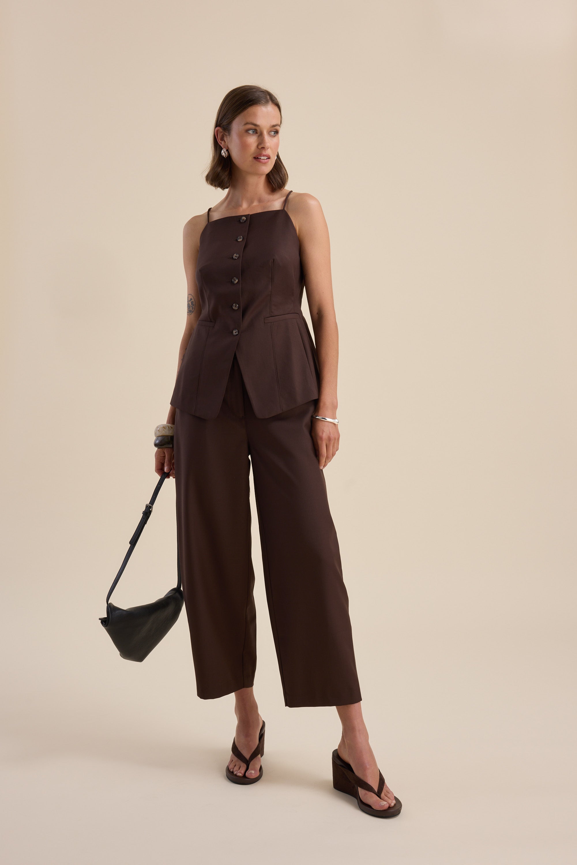 Woman in Max's The Wool Blend Vest and wide-leg pants, holding a black handbag.