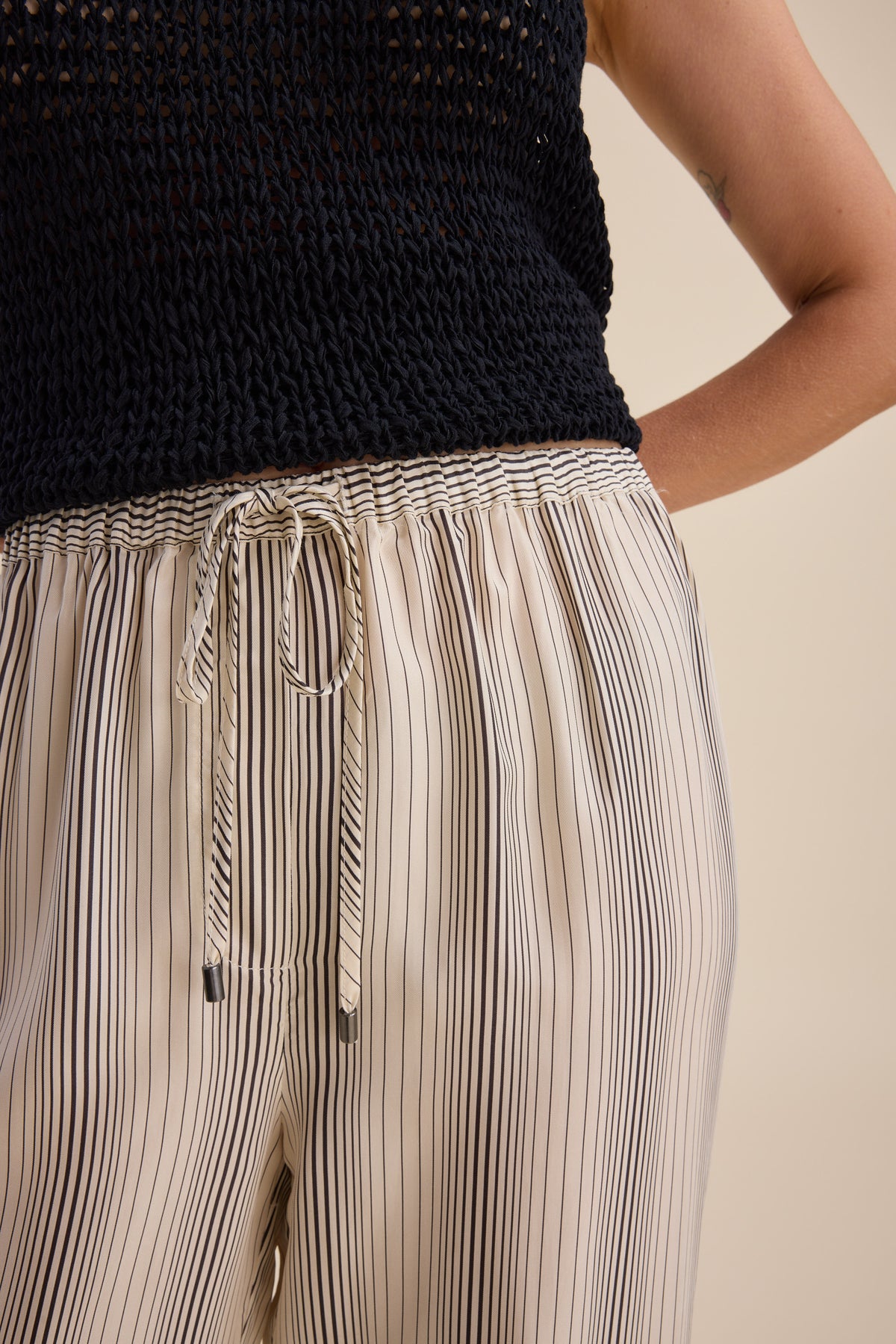 Person in a black knit top and Max Sera Drawstring Pants in cream with thin black stripes.