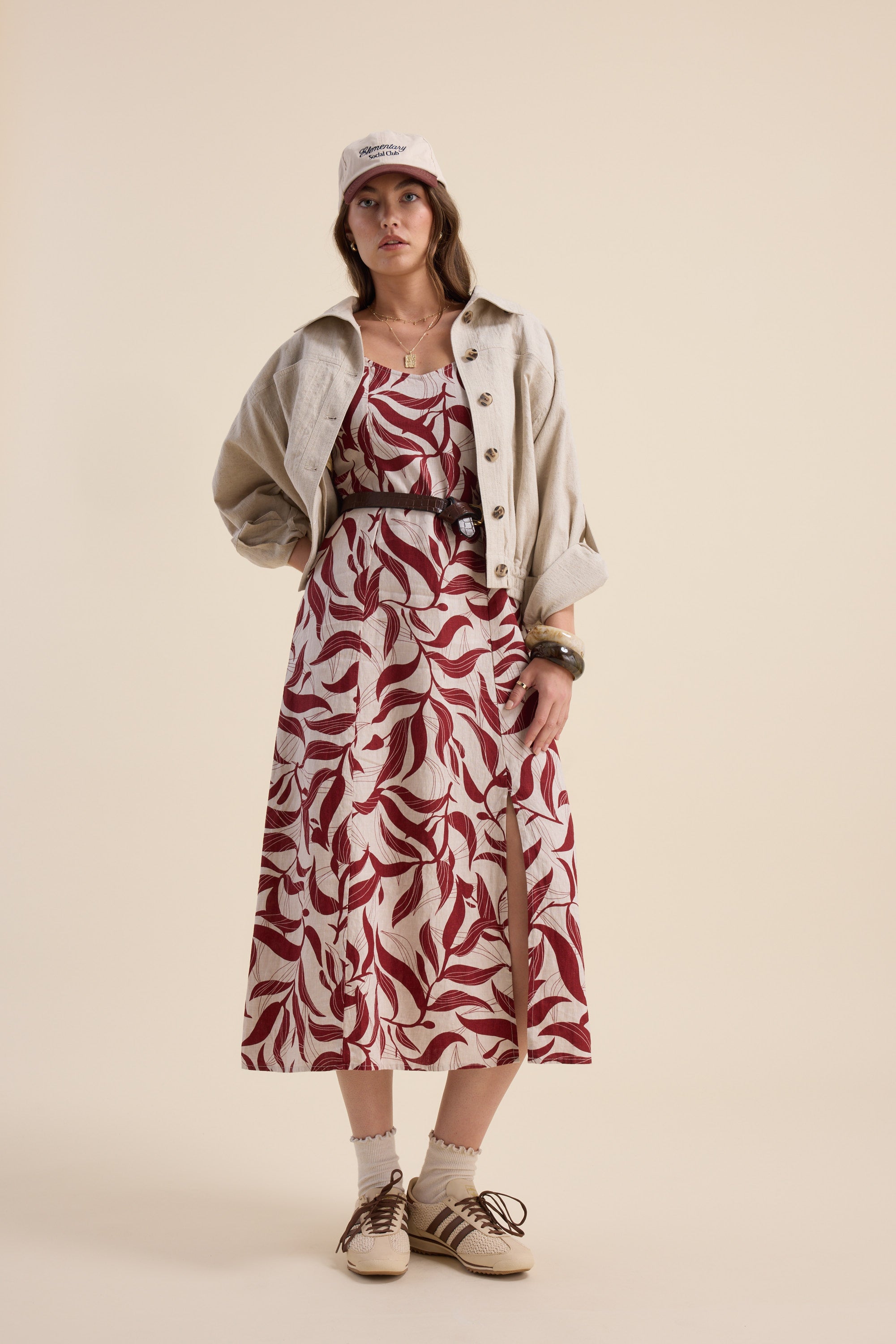 Woman in Max Camille Puff Sleeve Dress, cream jacket, tan hat, and beige shoes standing.