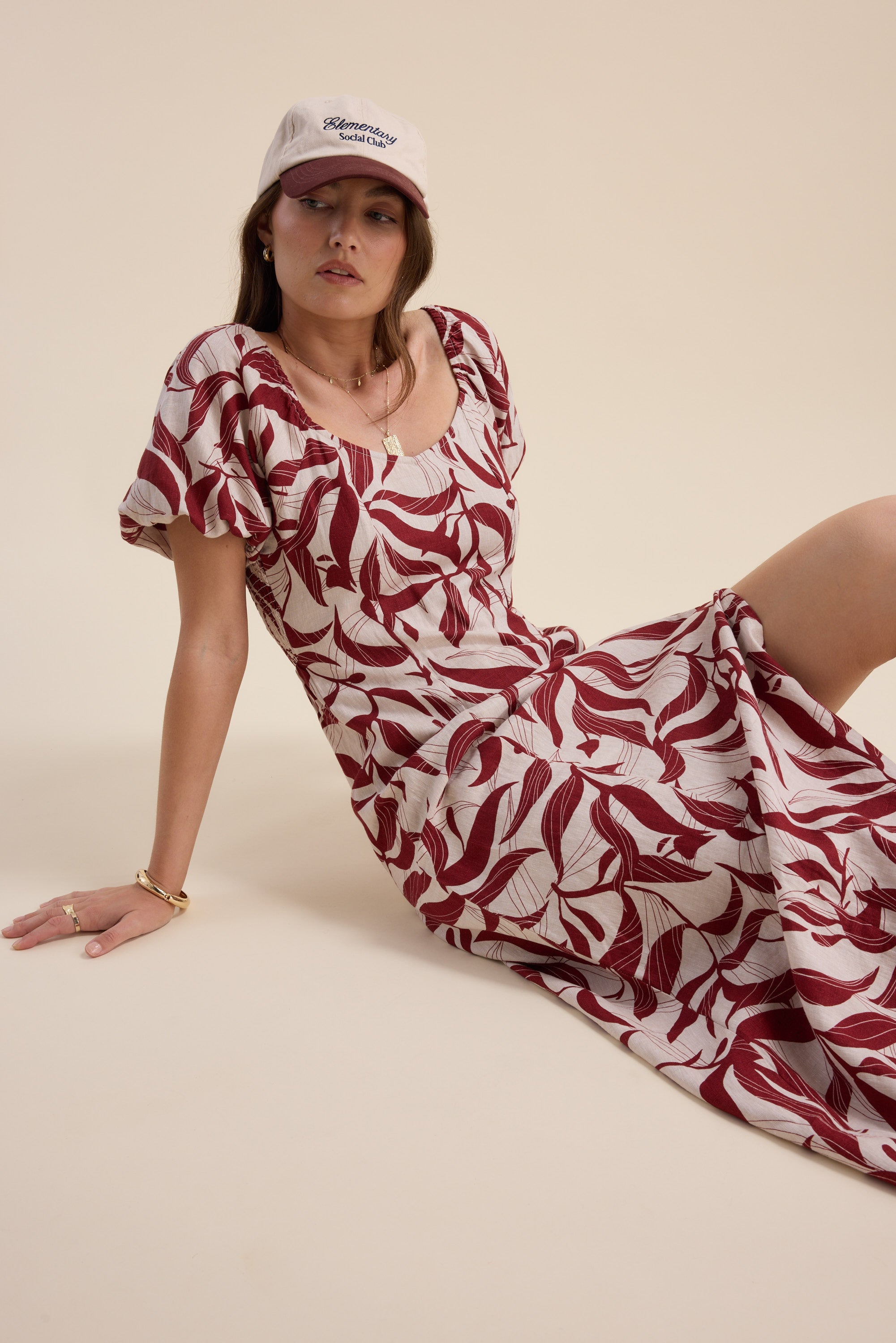 Woman in Camille Puff Sleeve Dress by Max sits on the floor against a beige background.