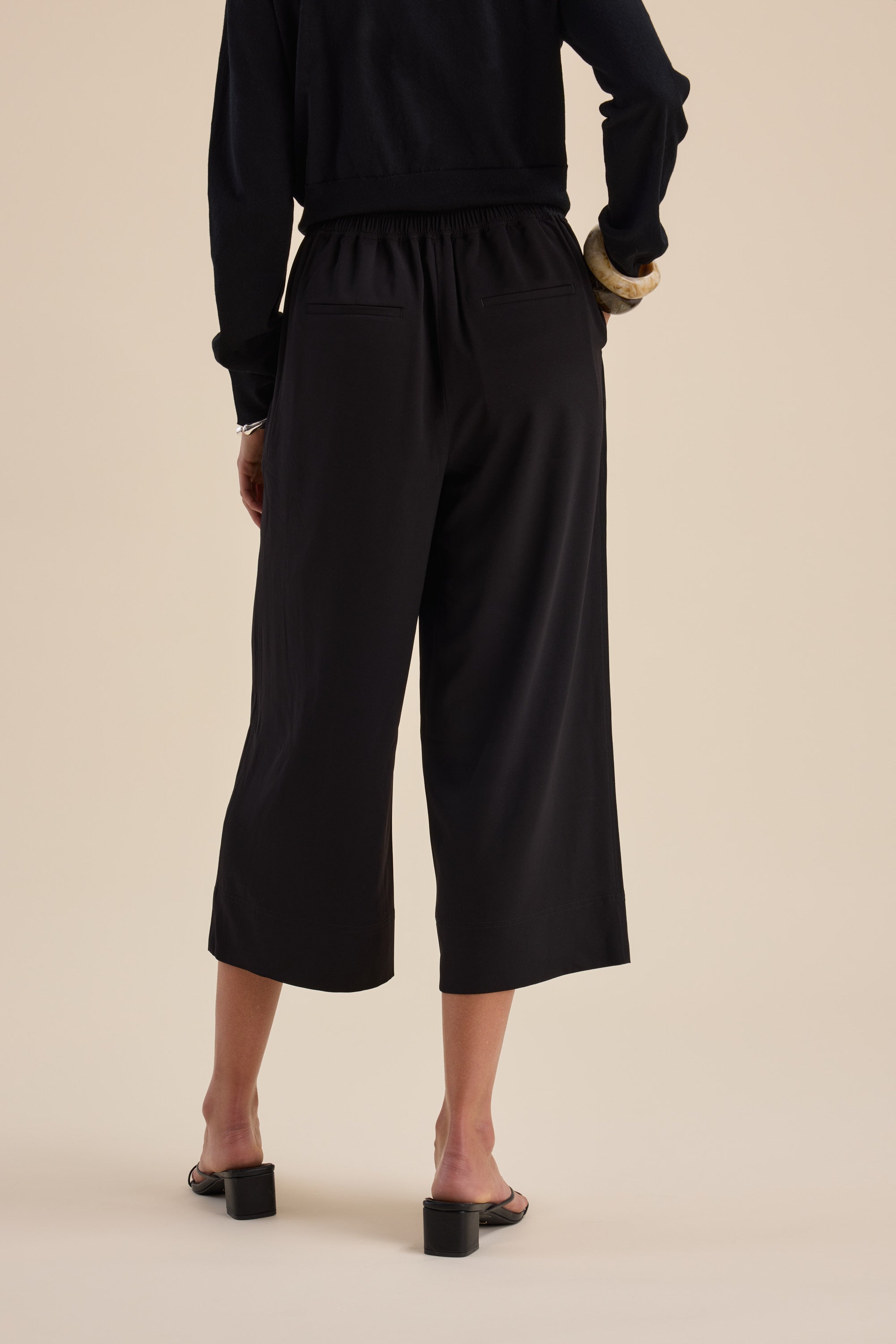 Model in Max’s The Easy Care Wide Leg Crop Pants and heels, shown from the back.
