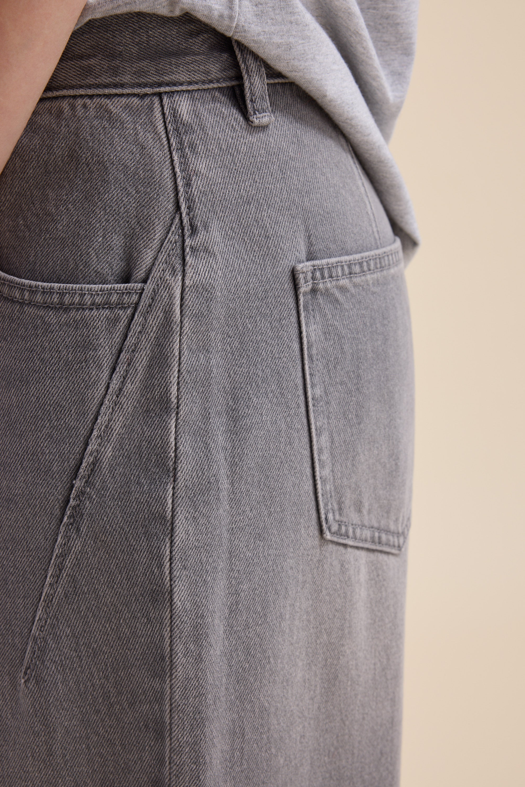Close-up of a person wearing Max The Barrel Leg Jeans and a light gray shirt.