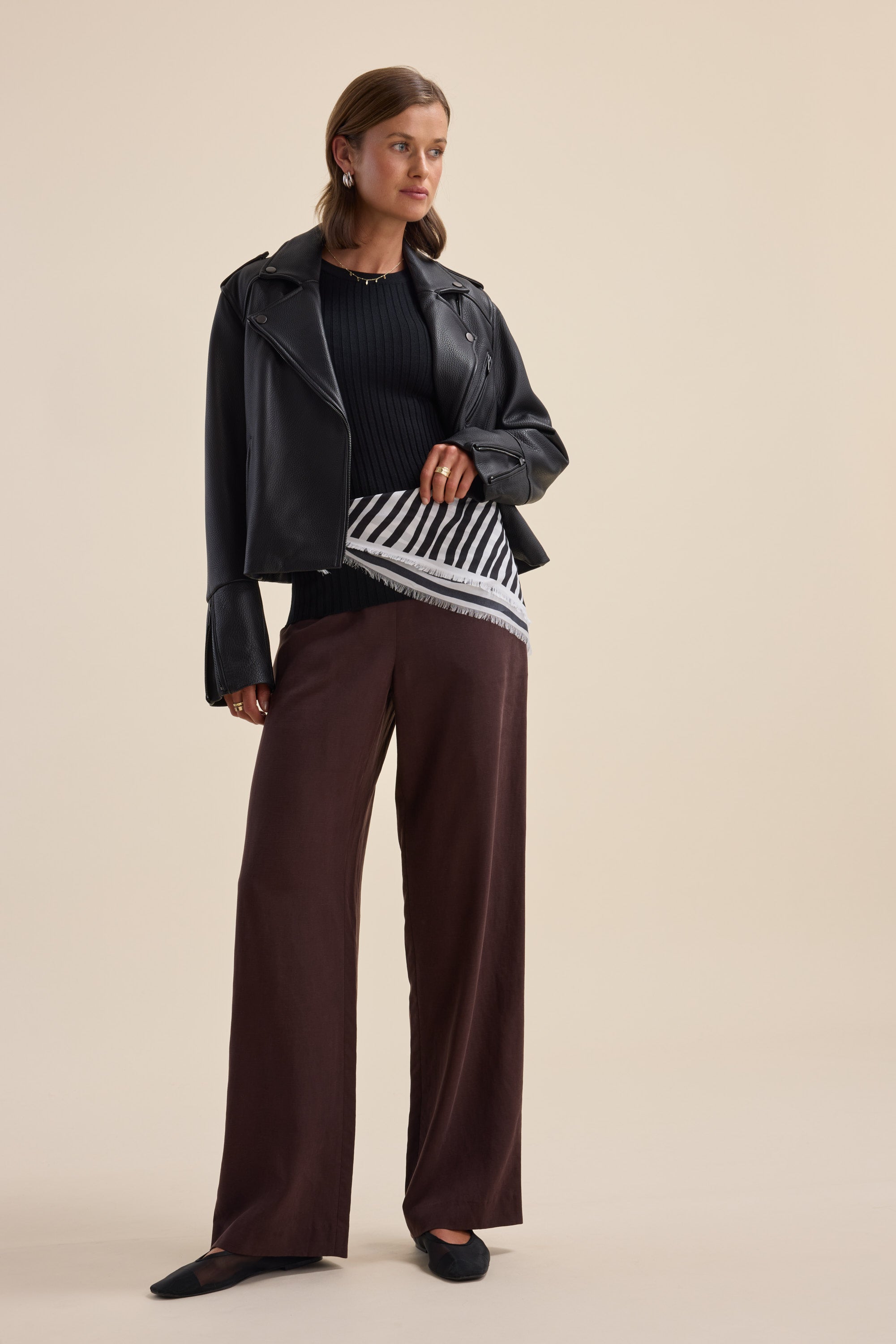 Woman in a leather jacket, Elementary ZQ Merino Crew Neck Top, wide brown pants, black flats.