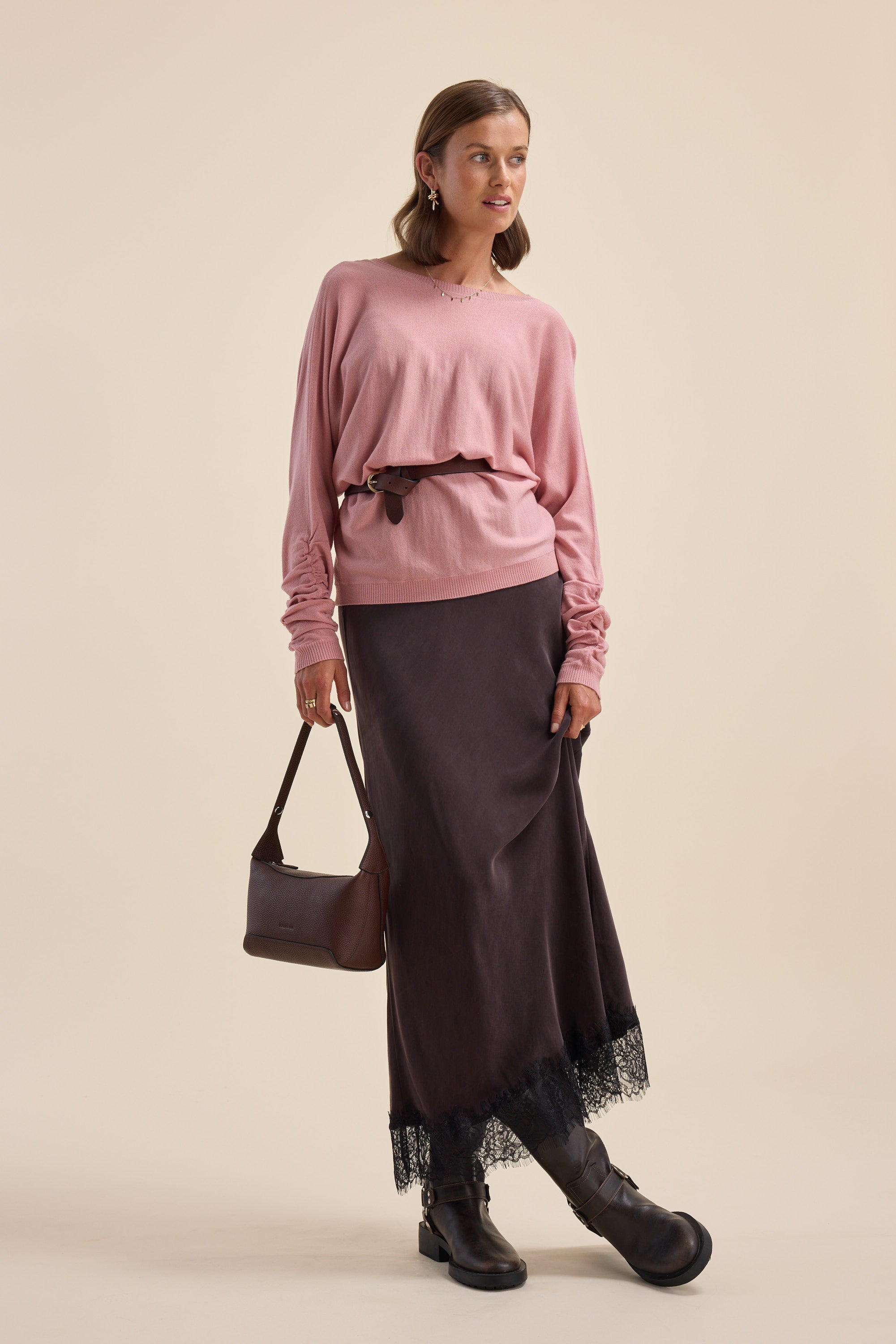Woman in Elementary ZQ Merino Reversible Sweater, black skirt, boots, with a brown handbag.