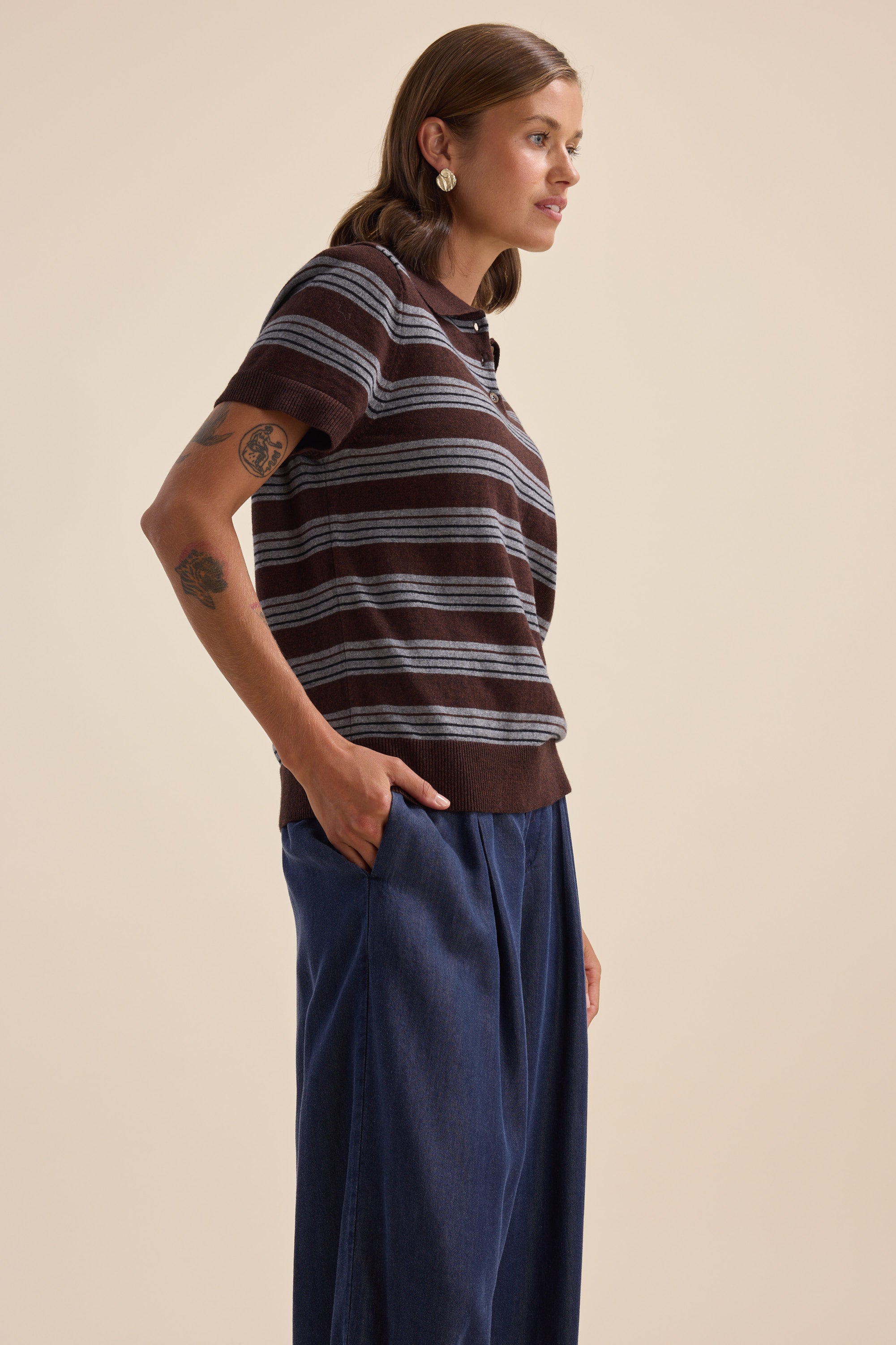 Woman in Elementary Cotton Cashmere Henley and blue wide-leg pants stands sideways against beige.